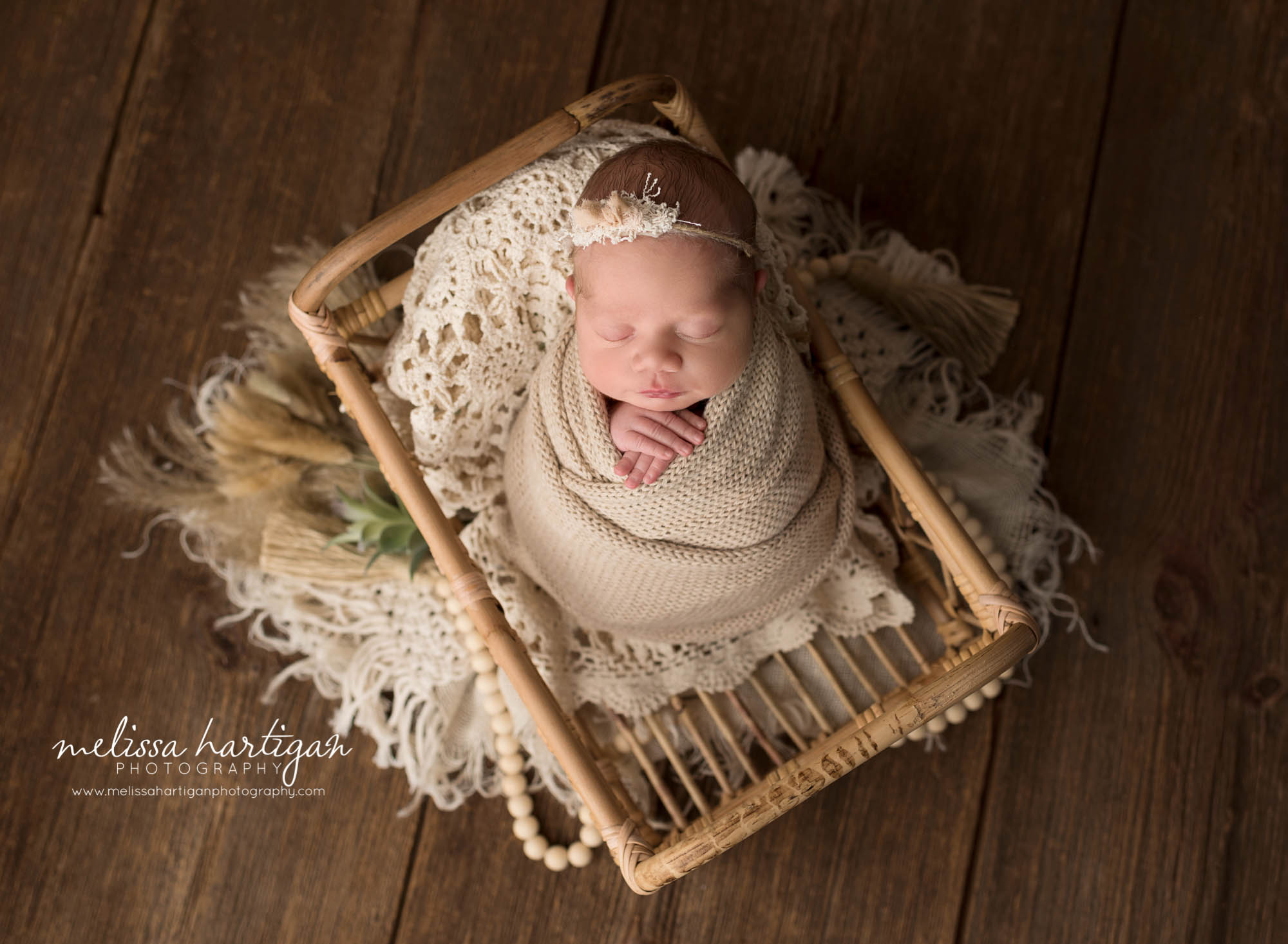 newborn baby girl wrapped in knitted wrap posed in basket