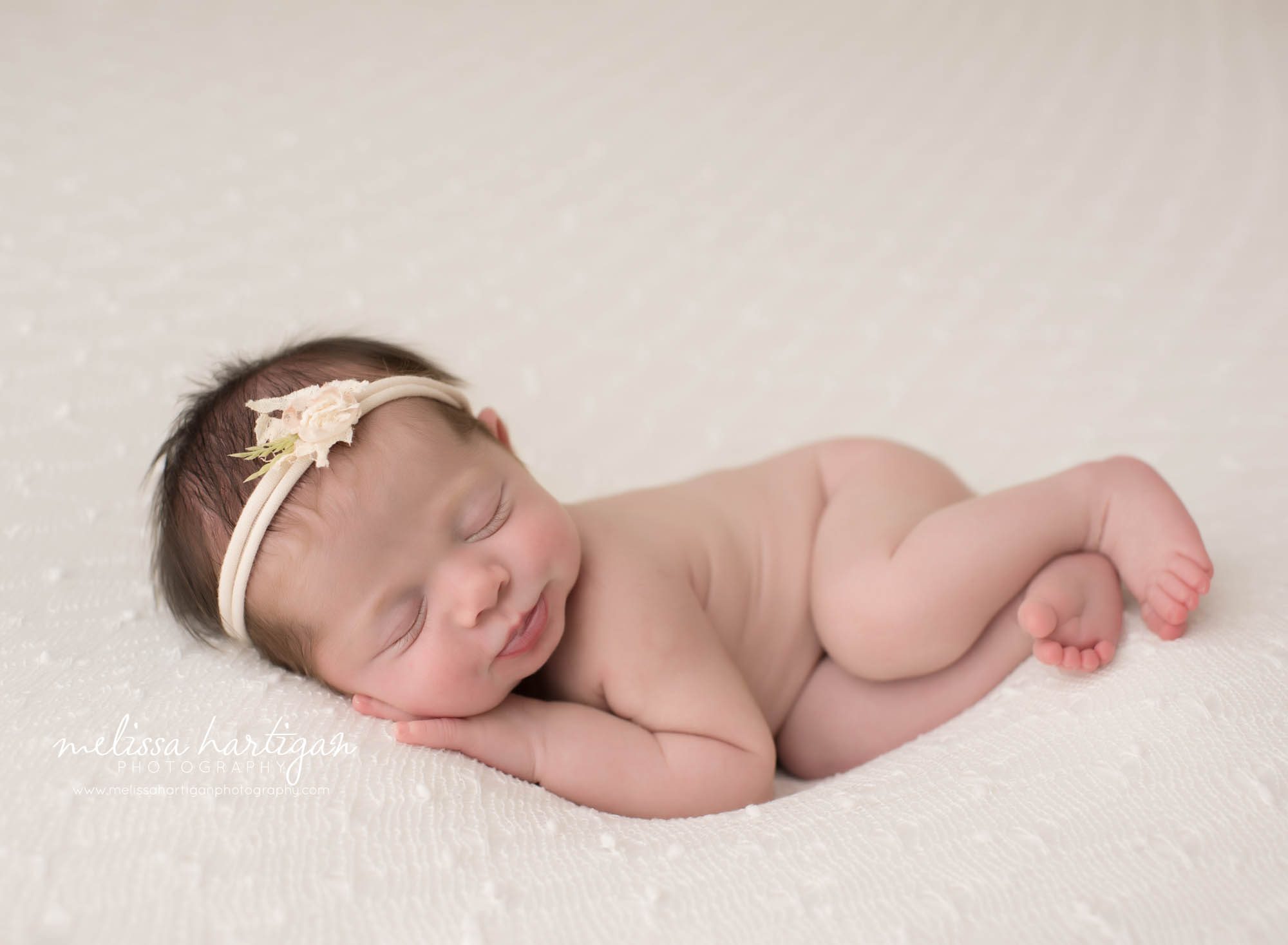 newborn baby girl posed on side with hand under cheek