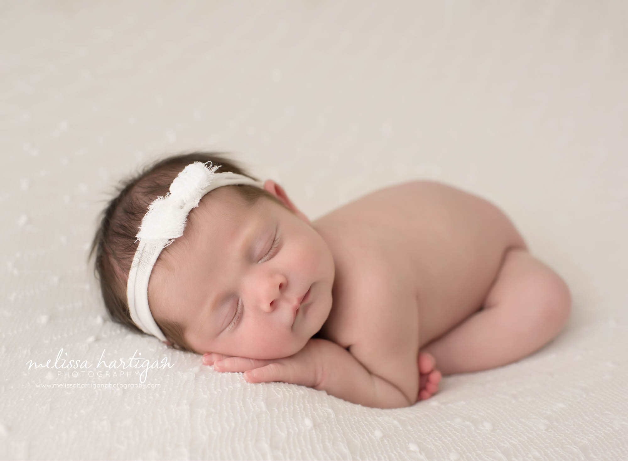 newborn baby girl posed modified taco pose wearing white headband colchester newborn photography