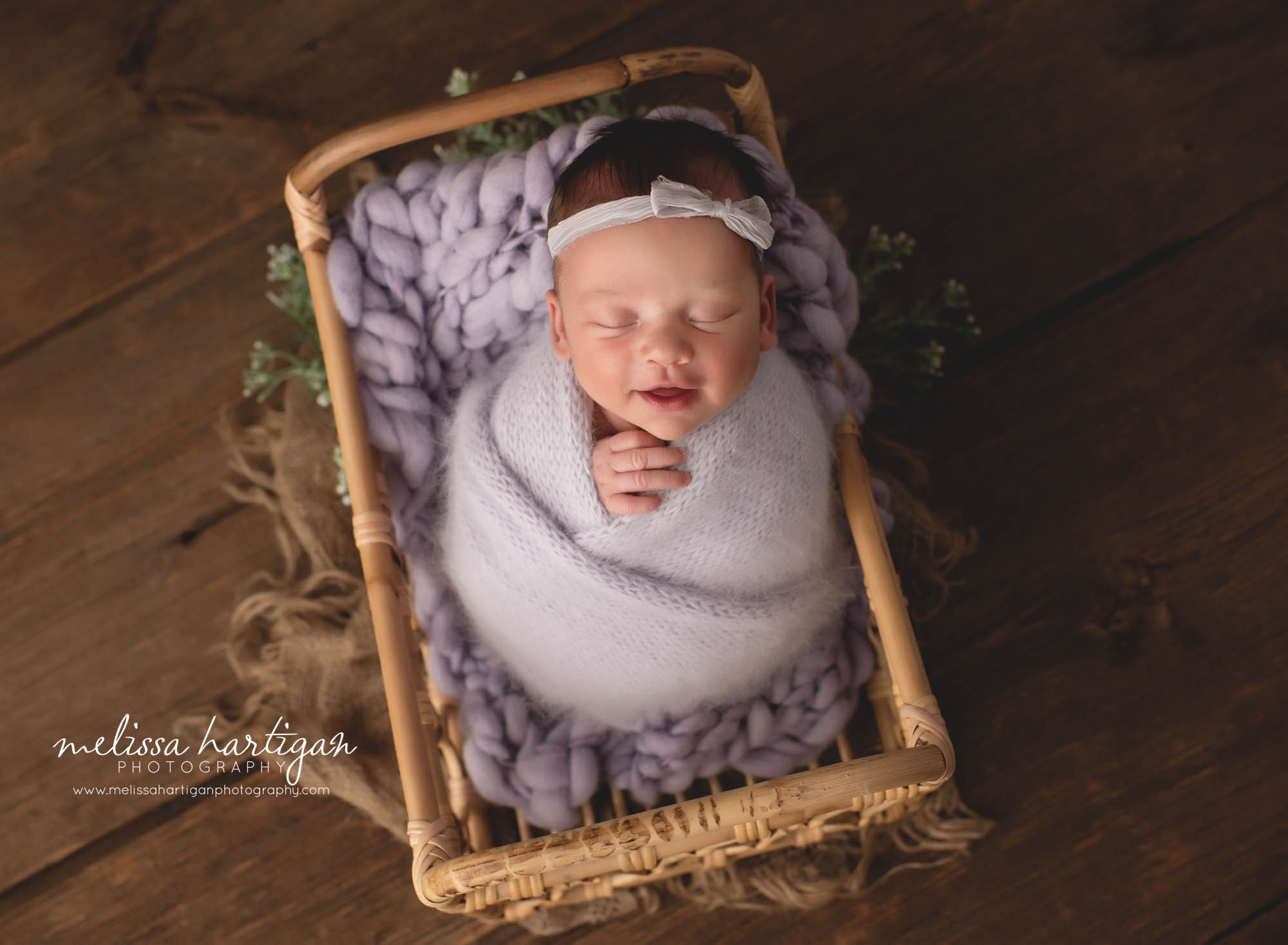 newborn baby girl wraped in knitted purple wrap posed in basket with purple knitted chunky layer connecticut newborn photography