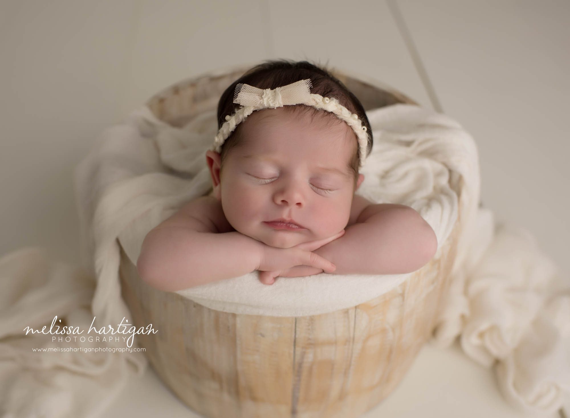 newborn baby girl posed in wooden barrel with bow headband Connecticut newborn photography
