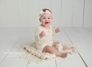 baby girl sitting on cream layer in photography studio