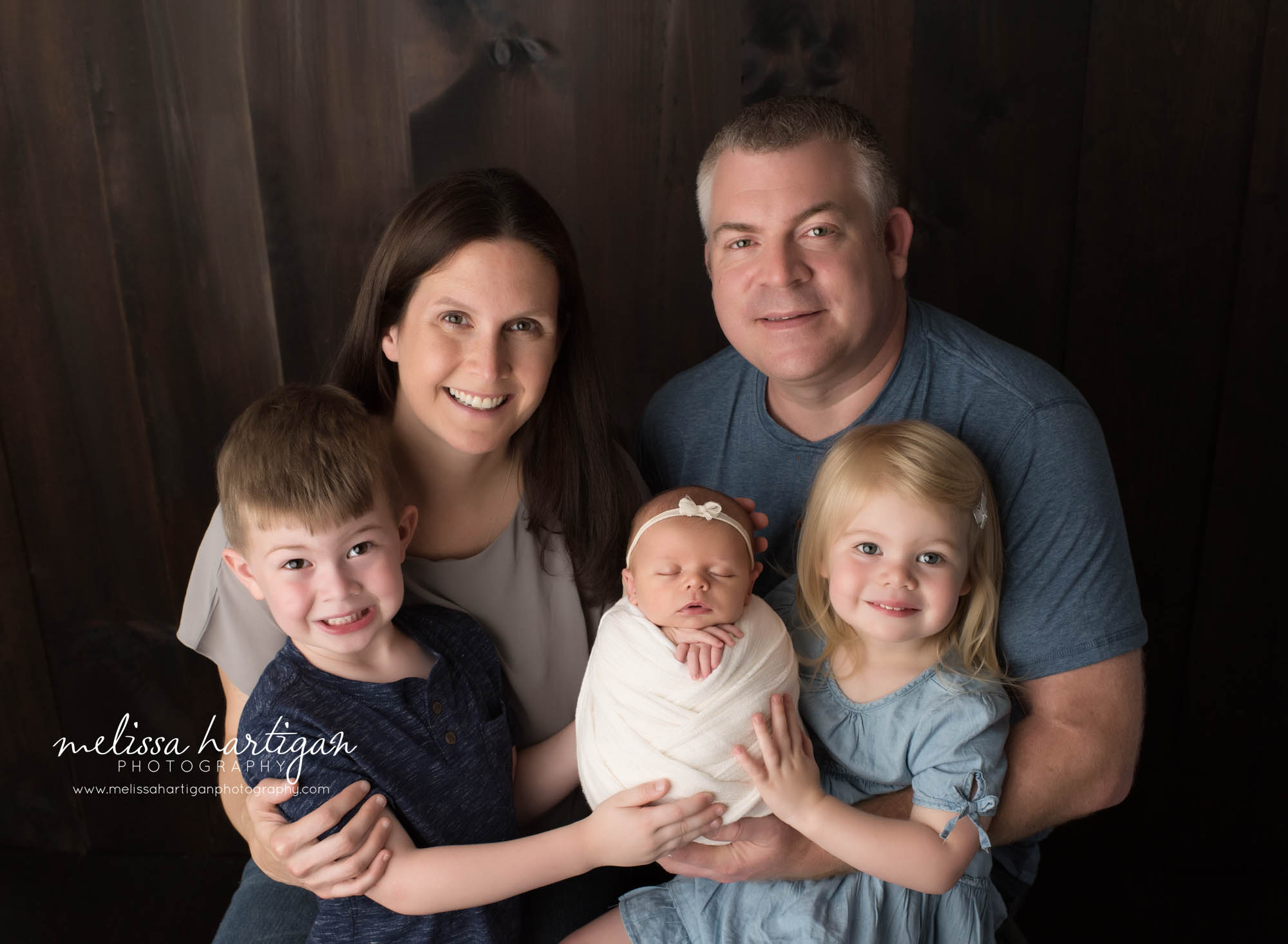 mom dad big brother big sister and newborn baby girl posed together for family pose
