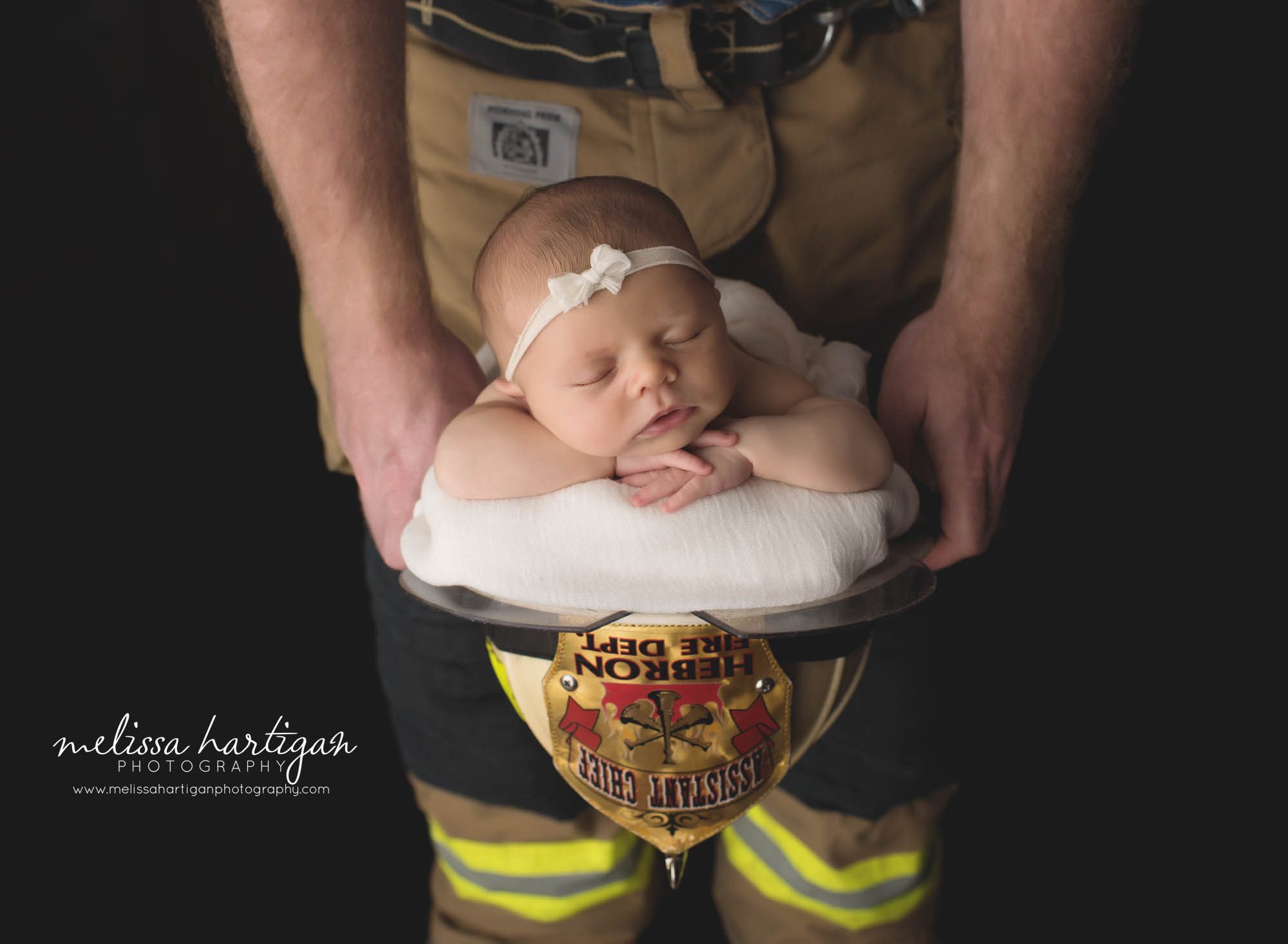 newborn baby girl posed in fire fighter hat newborn photography session setup
