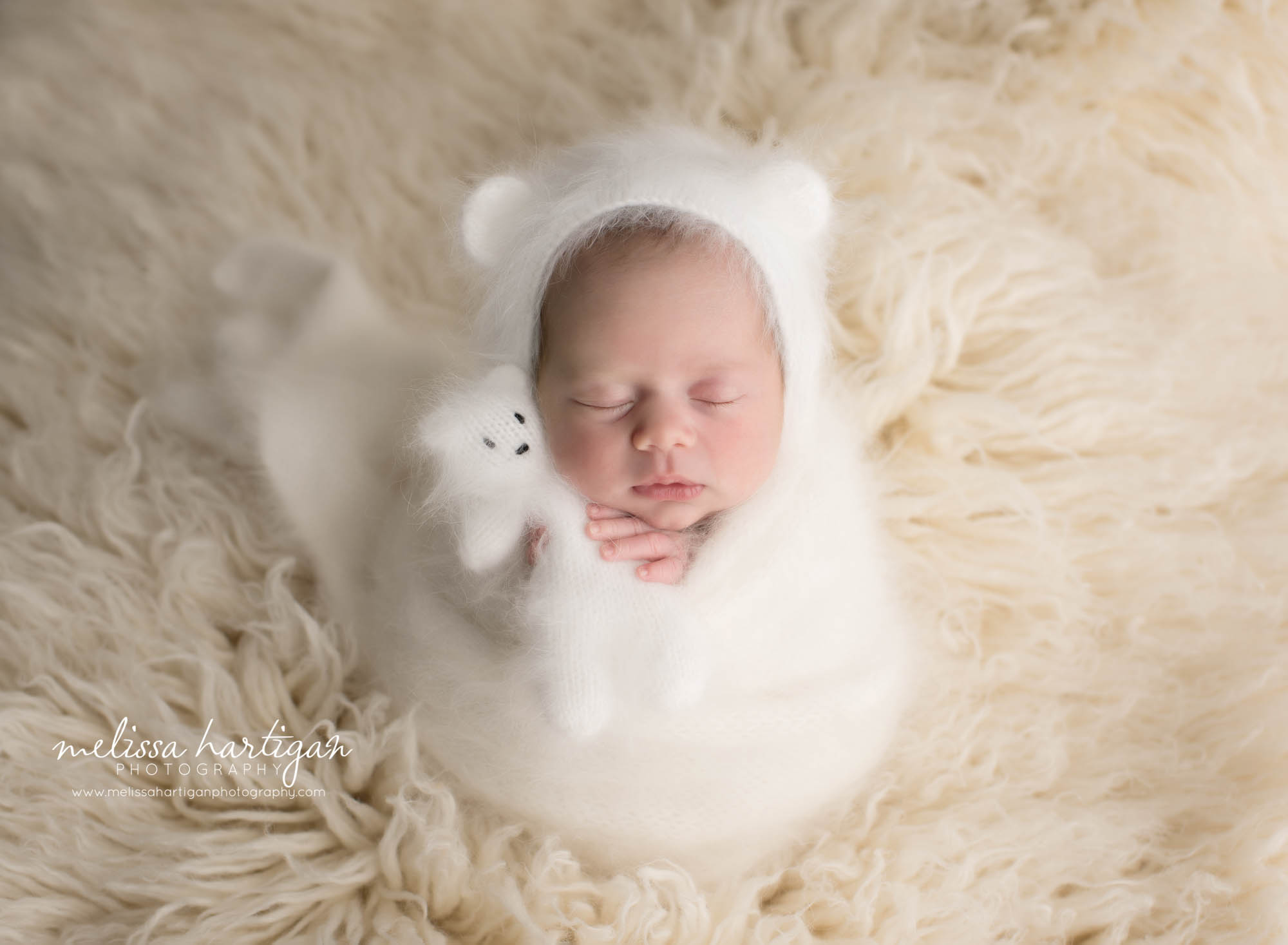 newborn baby girl wrapped in white knit wrap wearing white knit teddy bear bonnet holding matching knit teddy bear lovey CT newborn photographer