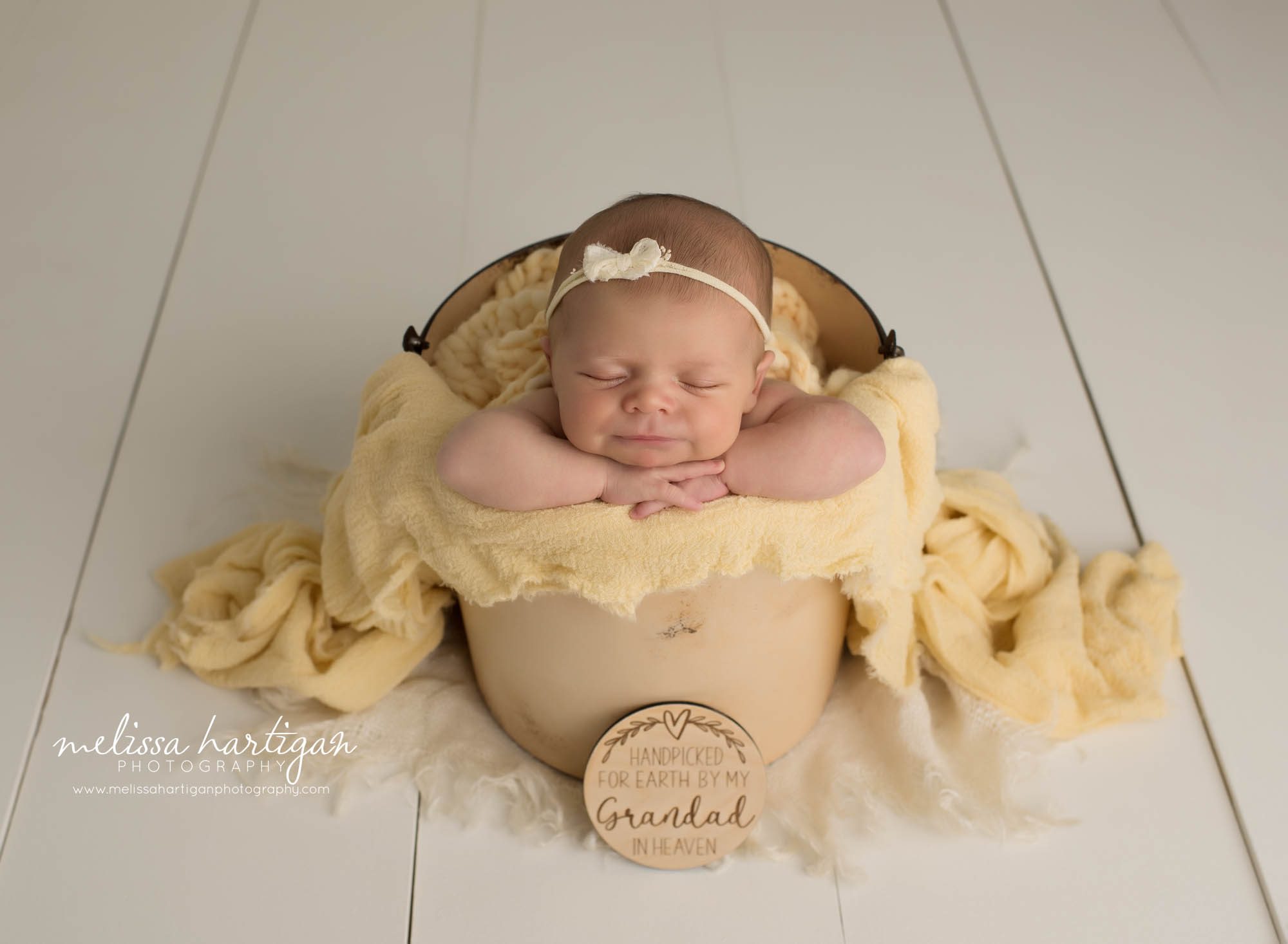 newborn baby girl posed in bucket with yellow draping and special message carved into wooden plaque CT newborn photography Amston CT