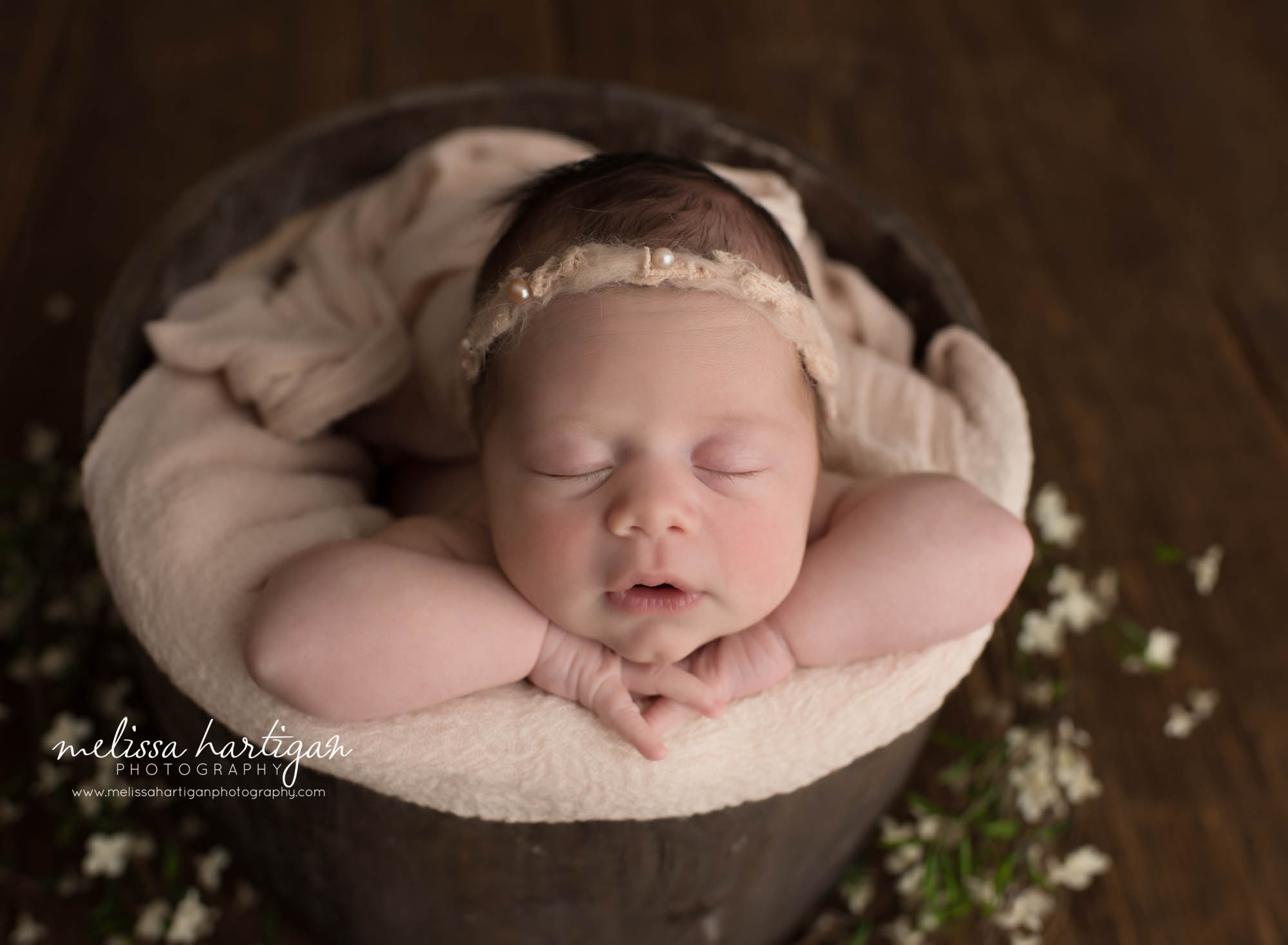 newborn baby girl posed in barrel bucket with light pink layer