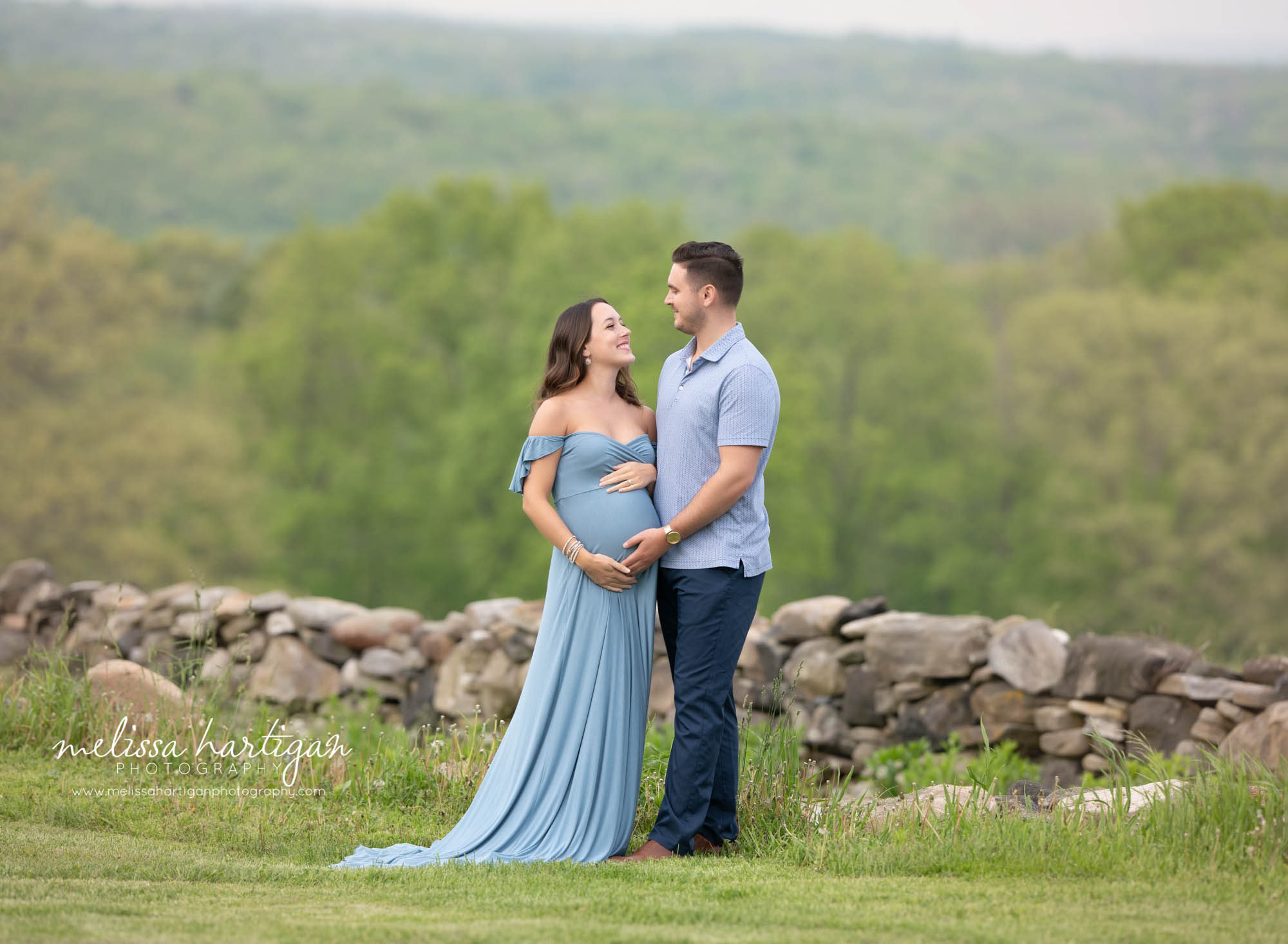 couple holding baby bump in connecticut park during maternity photoshoot