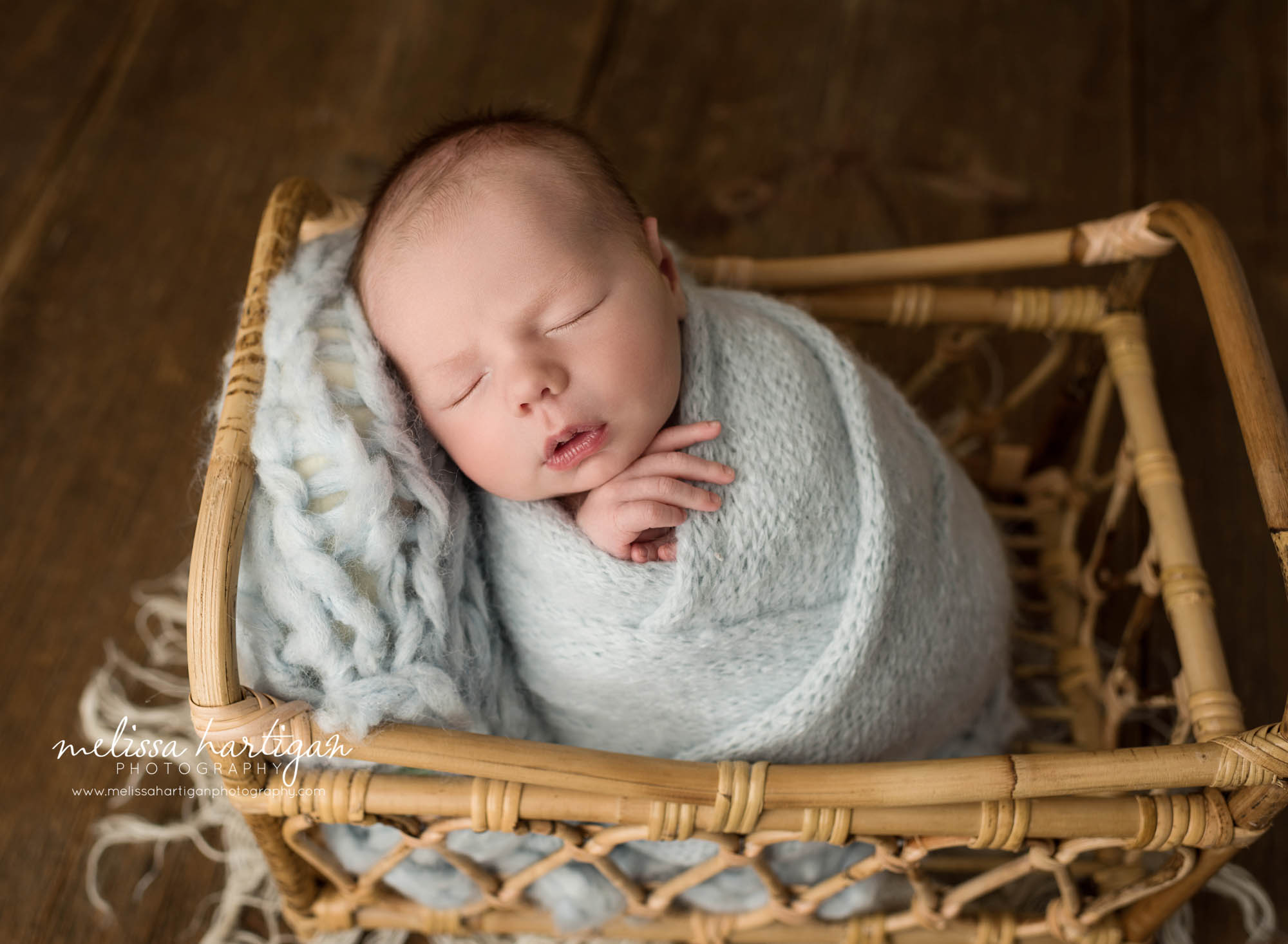 newborn baby boy wrapped in light blue knitted wrap posed in basket