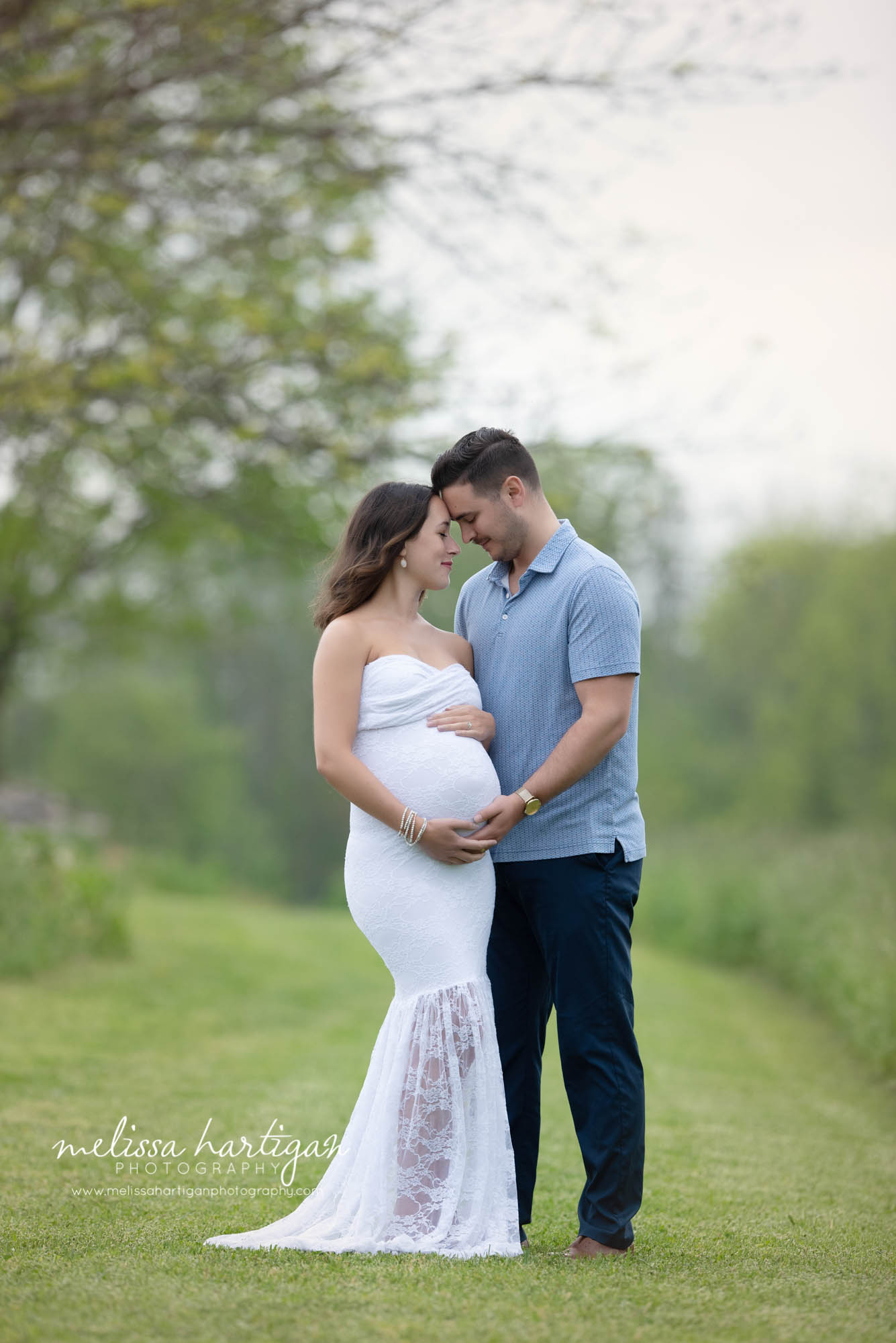 expectant couple standing together forehead to forehead