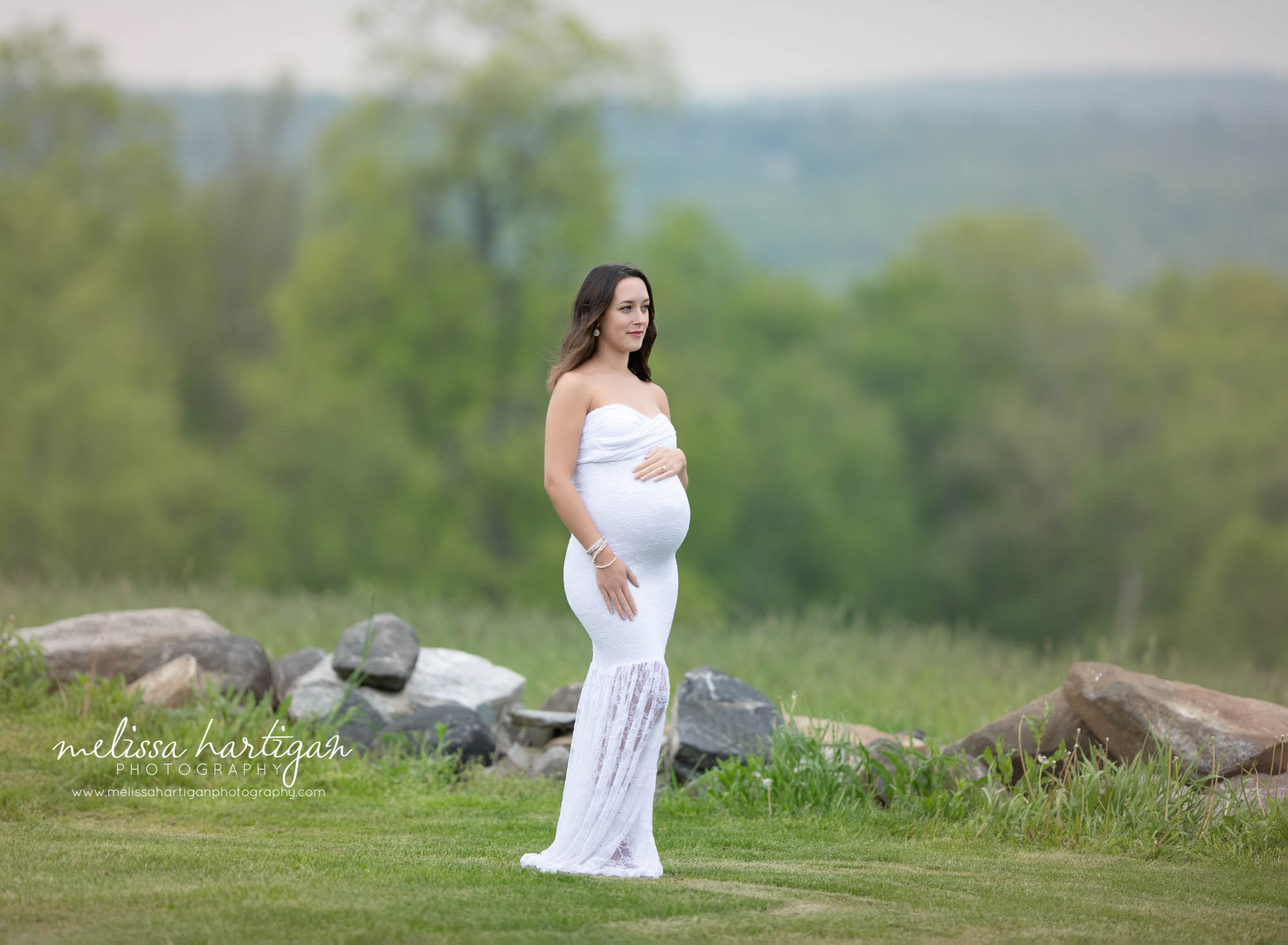 mom-to-be wearing white lace long form fitted maternity gown with hand on baby bump maternity photographer Connecticut