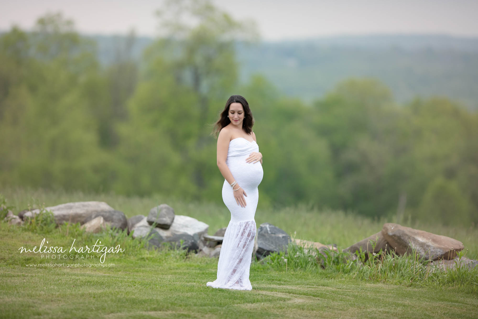 mom-to-be wearing white lace long form fitted maternity gown with hand on baby bump maternity photography CT