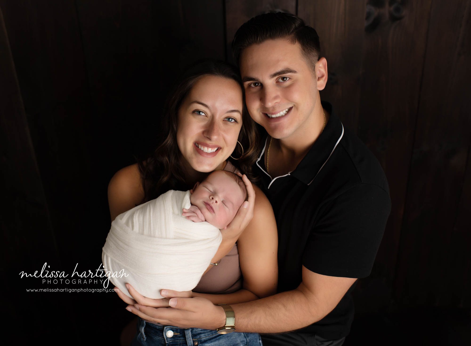 mom dad holding newborn son in family photo pose