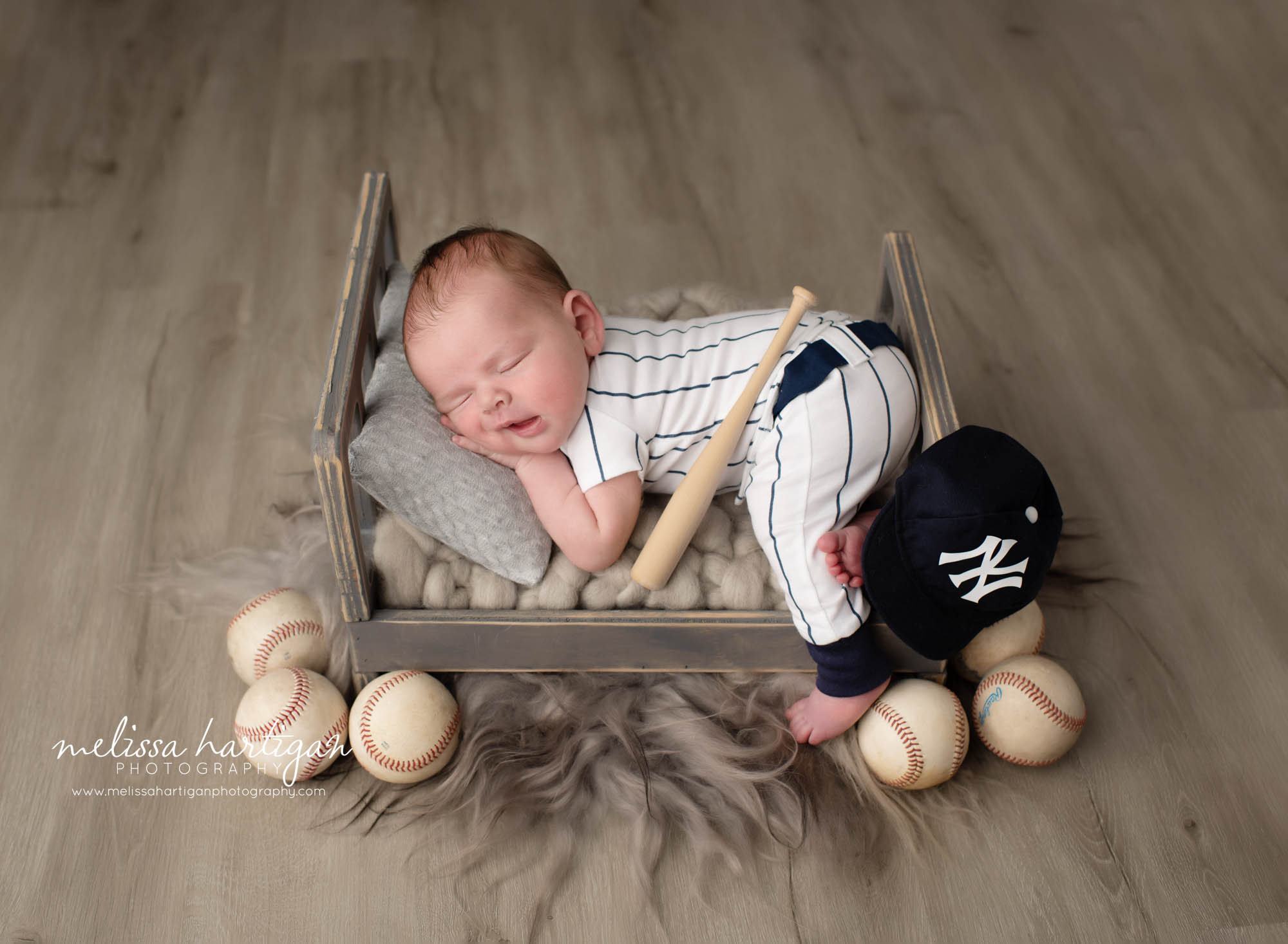 newborn baby boy posed on tummy on bed prop in baseball themed newborn photography setup maternity newborn photography Connecticut