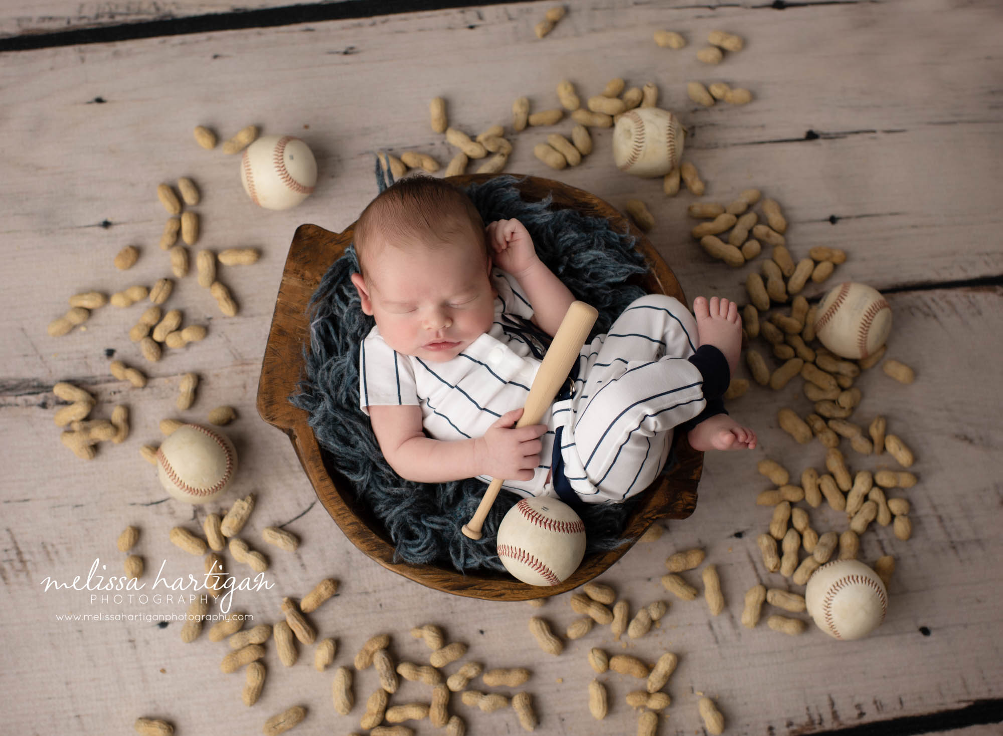 newborn baby boy posed in wooden bowl wearing yankee baseball outfit
