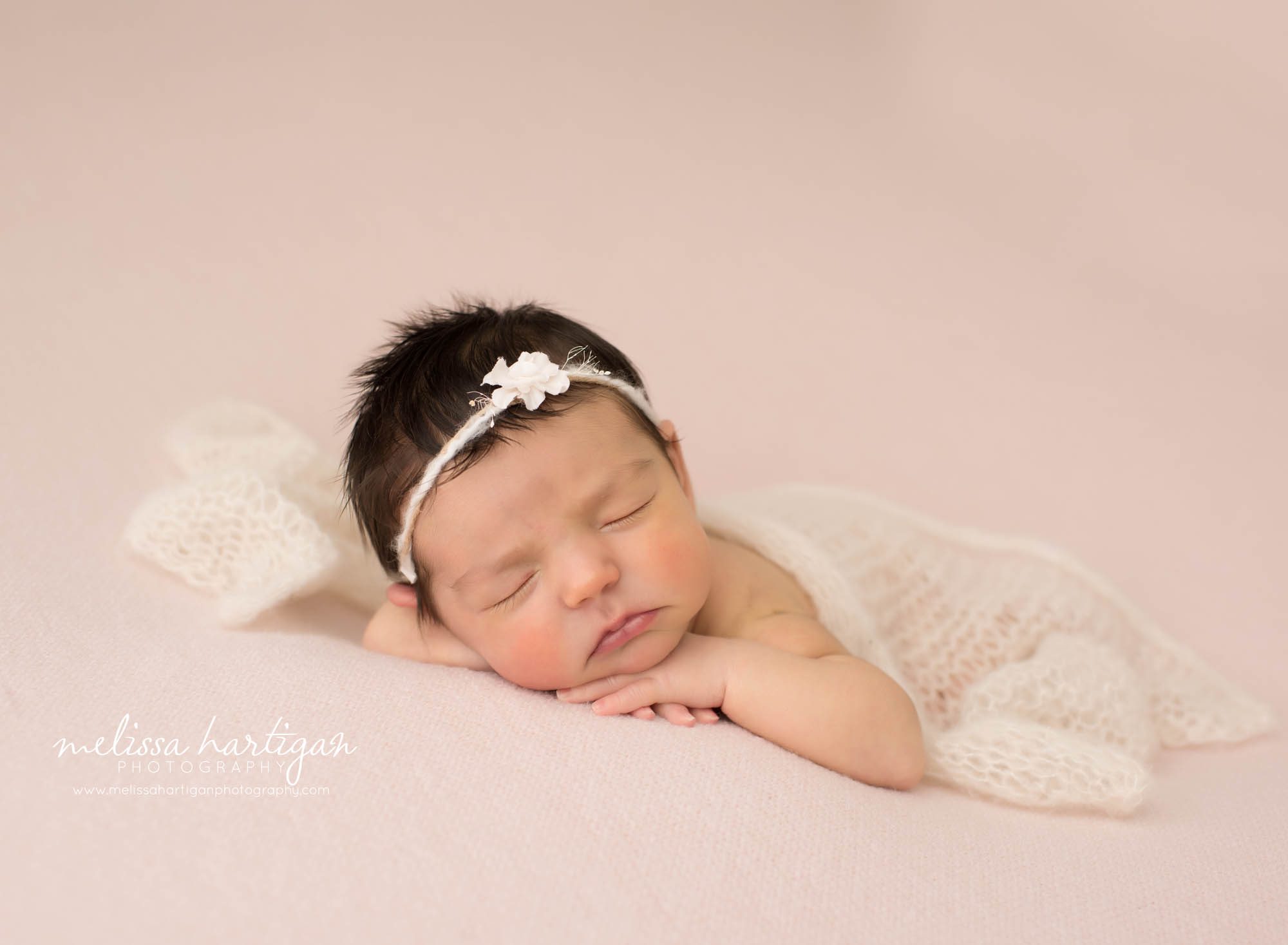 newborn baby girl posed on tummy with hands resting under chin