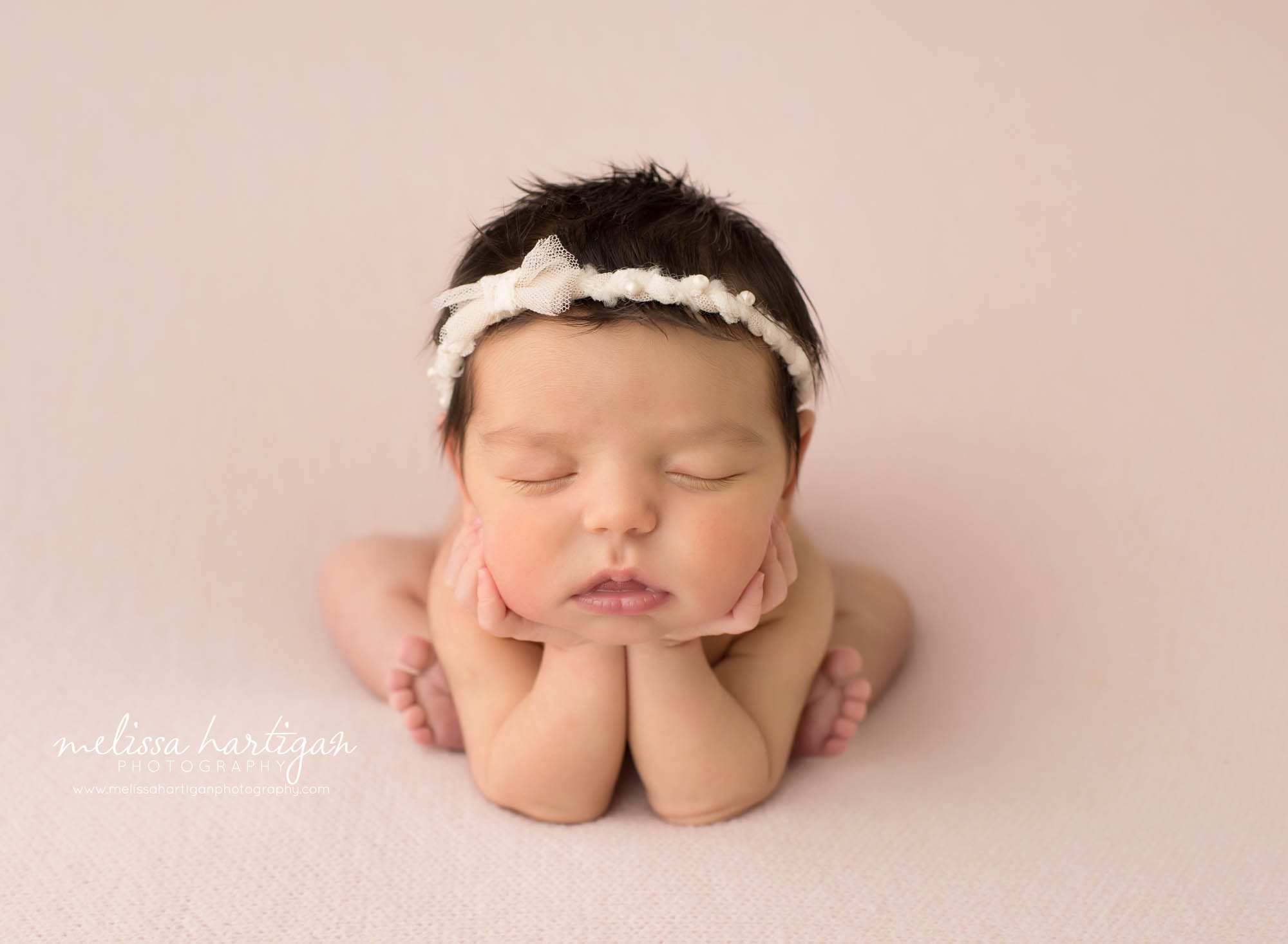 newborn baby girl posed on pink backdrop posed froggy pose