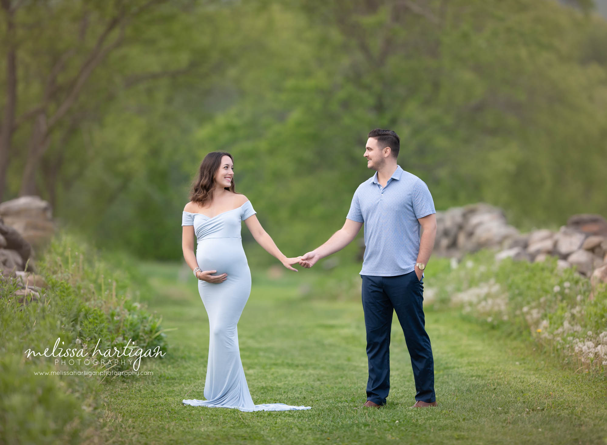 pregnant couple holding hands during maternity session in park