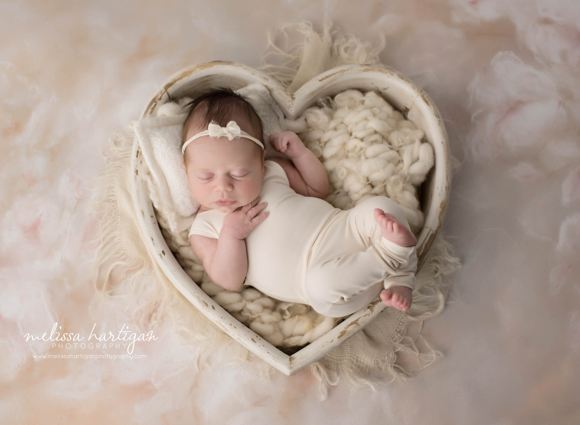 newborn baby girl wearing baby girl cream colored outfit posed in cream wooden heart bowl prop windsor locks ct baby photogaphy