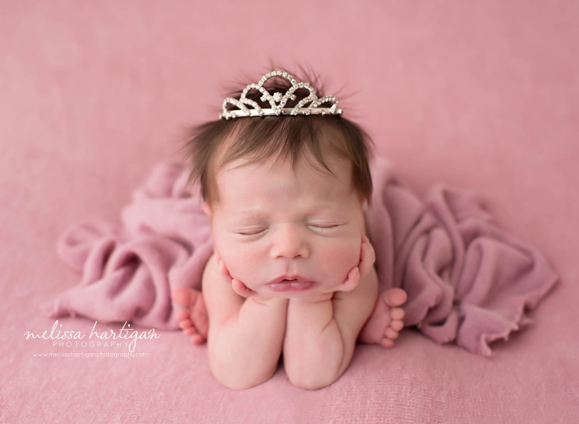 newborn baby girl posed froggy pose wearing crown on head