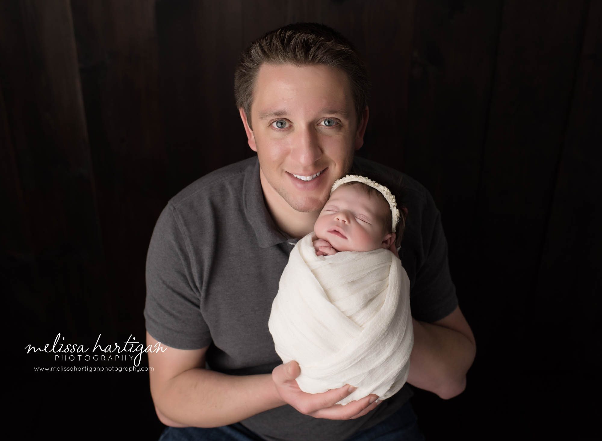 dad holding newborn baby daughter wrapped up studio parents pose