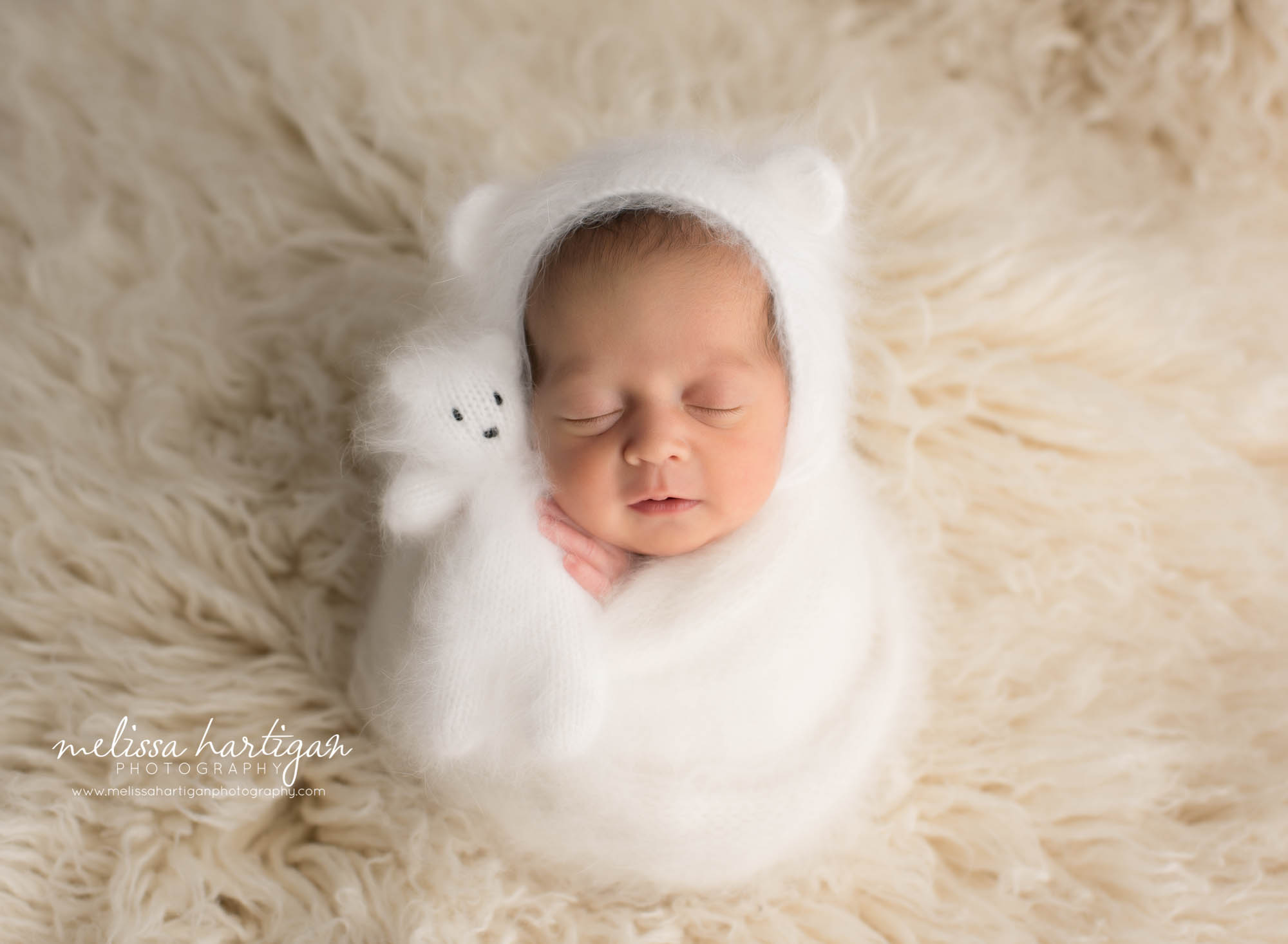 newborn baby girl wrapped in knitted wraped holding knitted teddy bear wearing matching knitted bear bonnet CT newborn Photography
