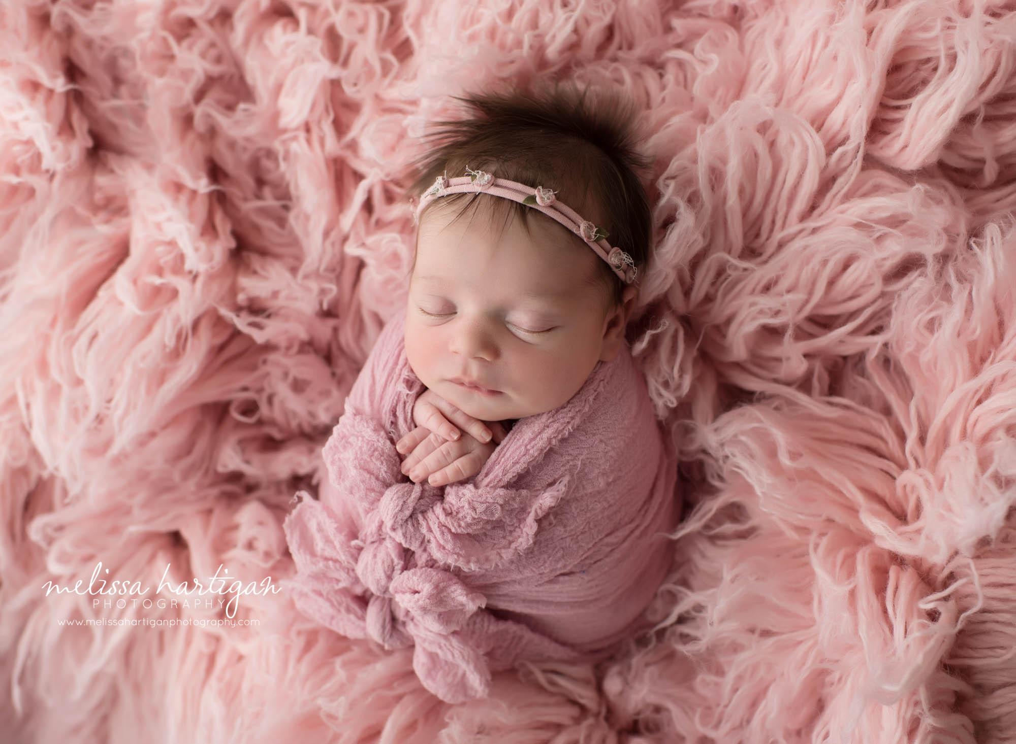 newborn baby girl wrapped in pink wrap with bows pose don flokati
