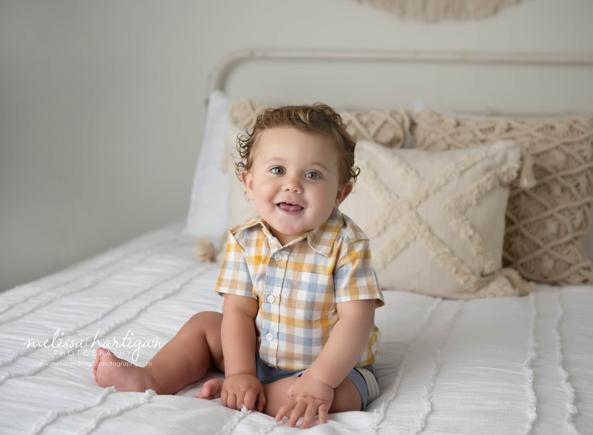 baby boy sitting on bed happy smiling