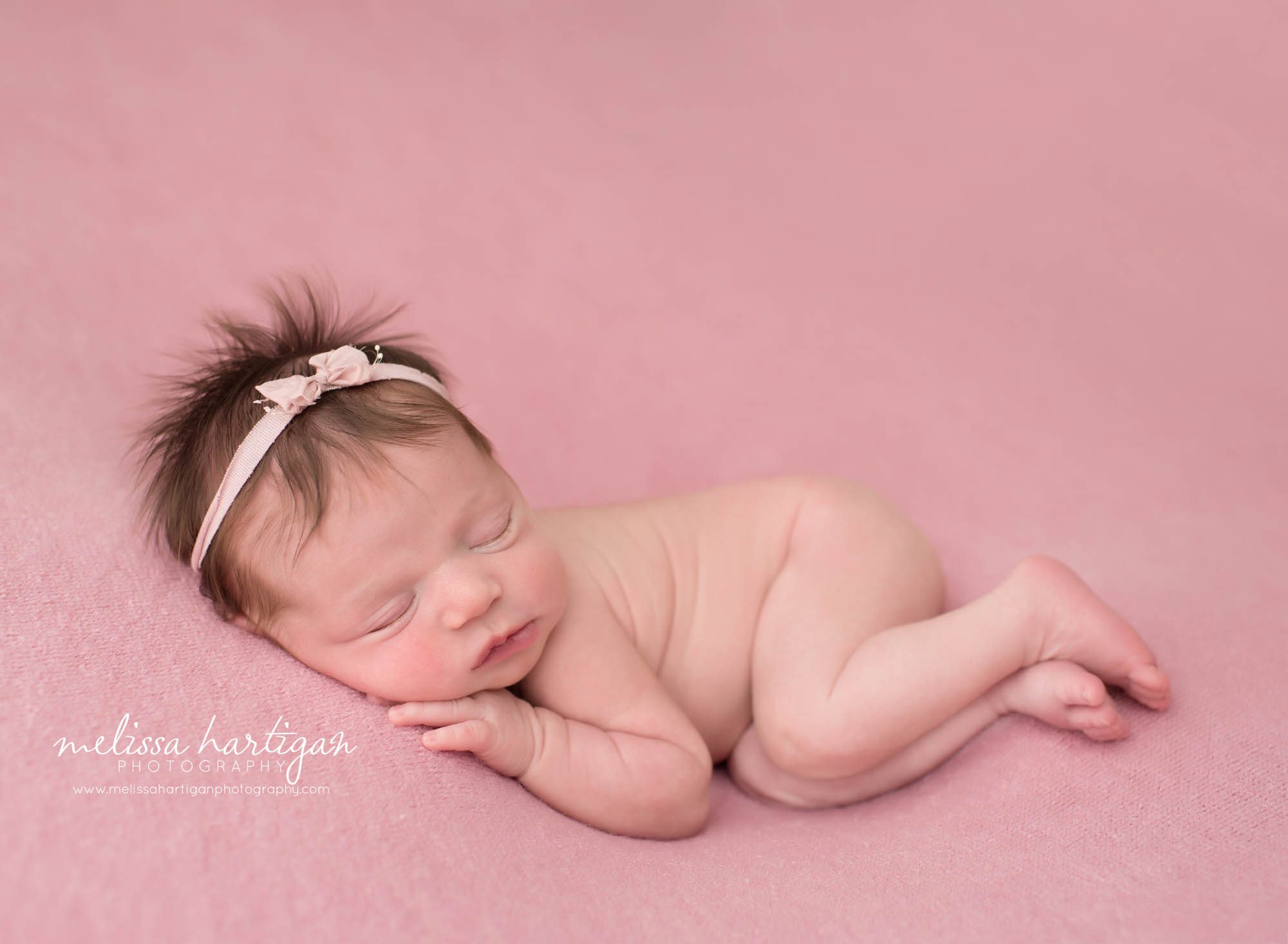 newborn baby girl posed on side on pink backdrop wearing pink bow headband CT maternity newborn photography