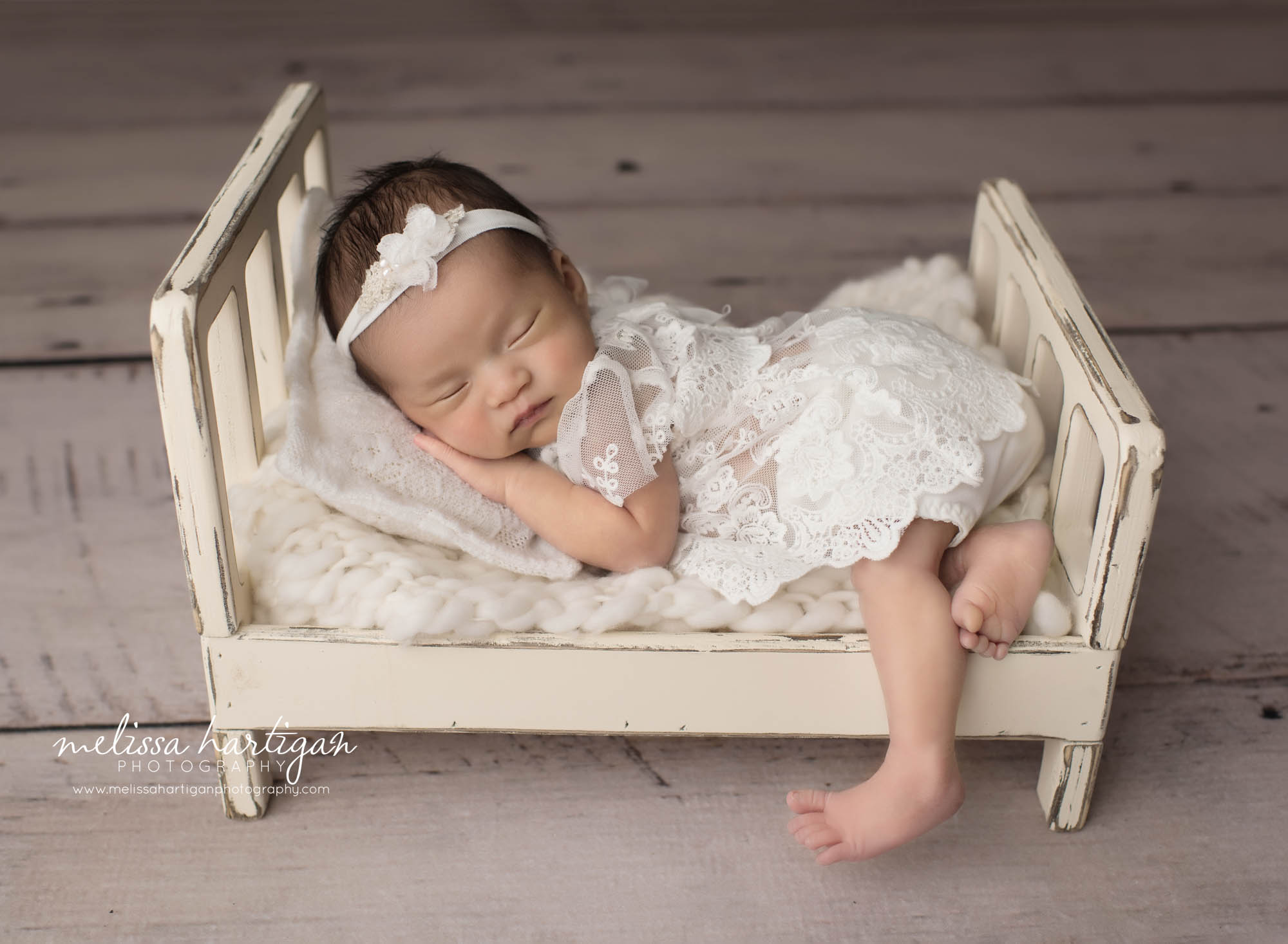 newborn baby girl posed on cream bed wearing floral lace newborn baby girl outfit