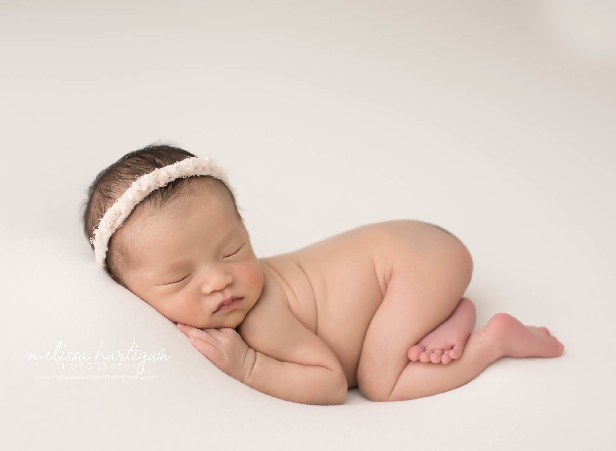 newborn baby girl posed on tummy wearing headba hartford county ct newborn photography