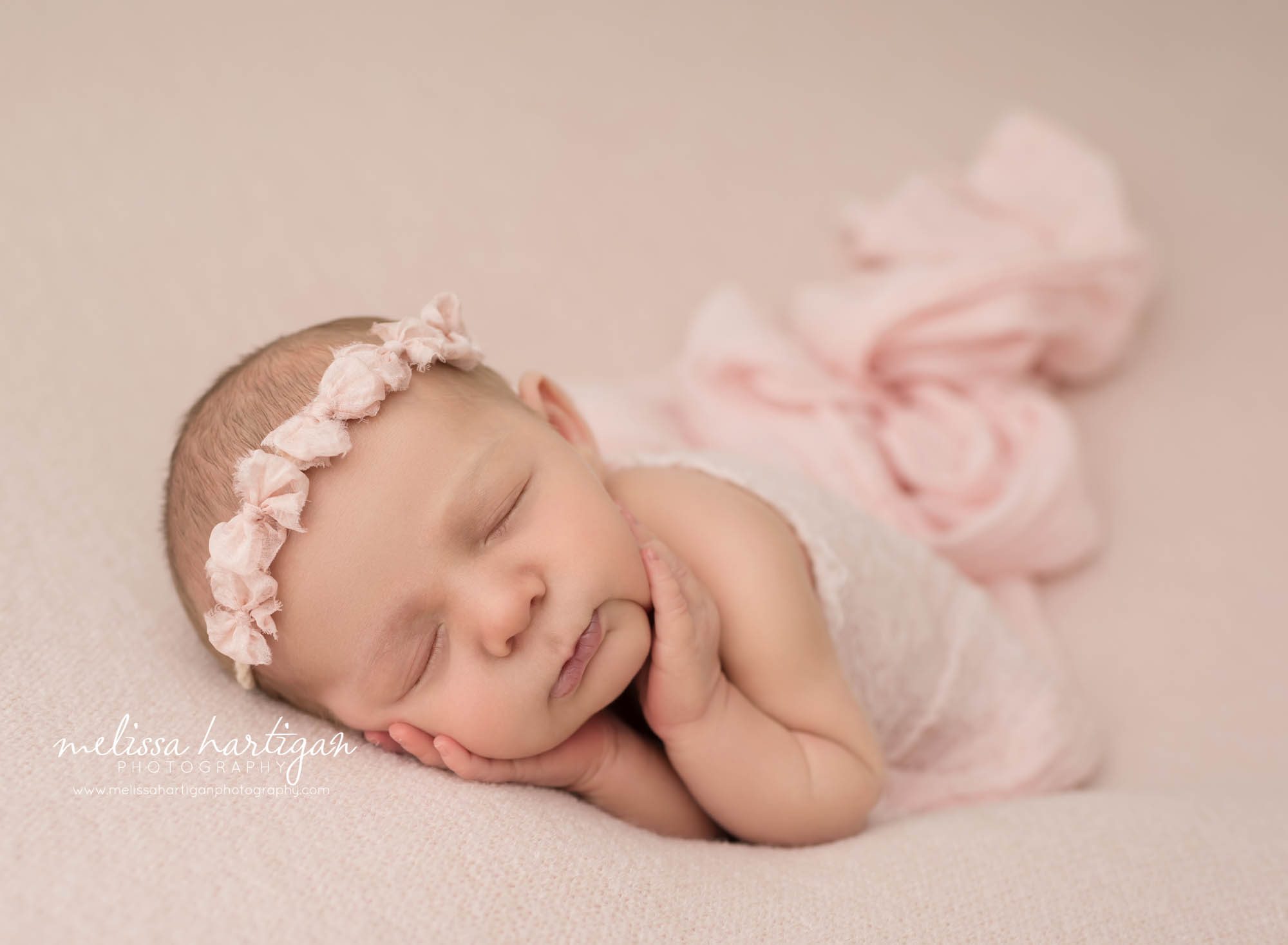 newborn baby girl posed on side wearing pink bow headband