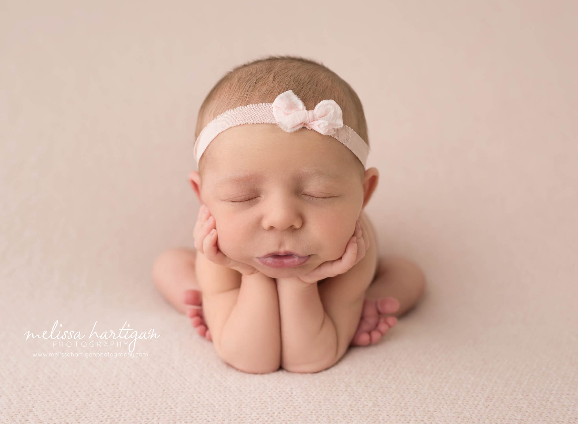 newborn baby girl posed on pink backdrop in froggy pose