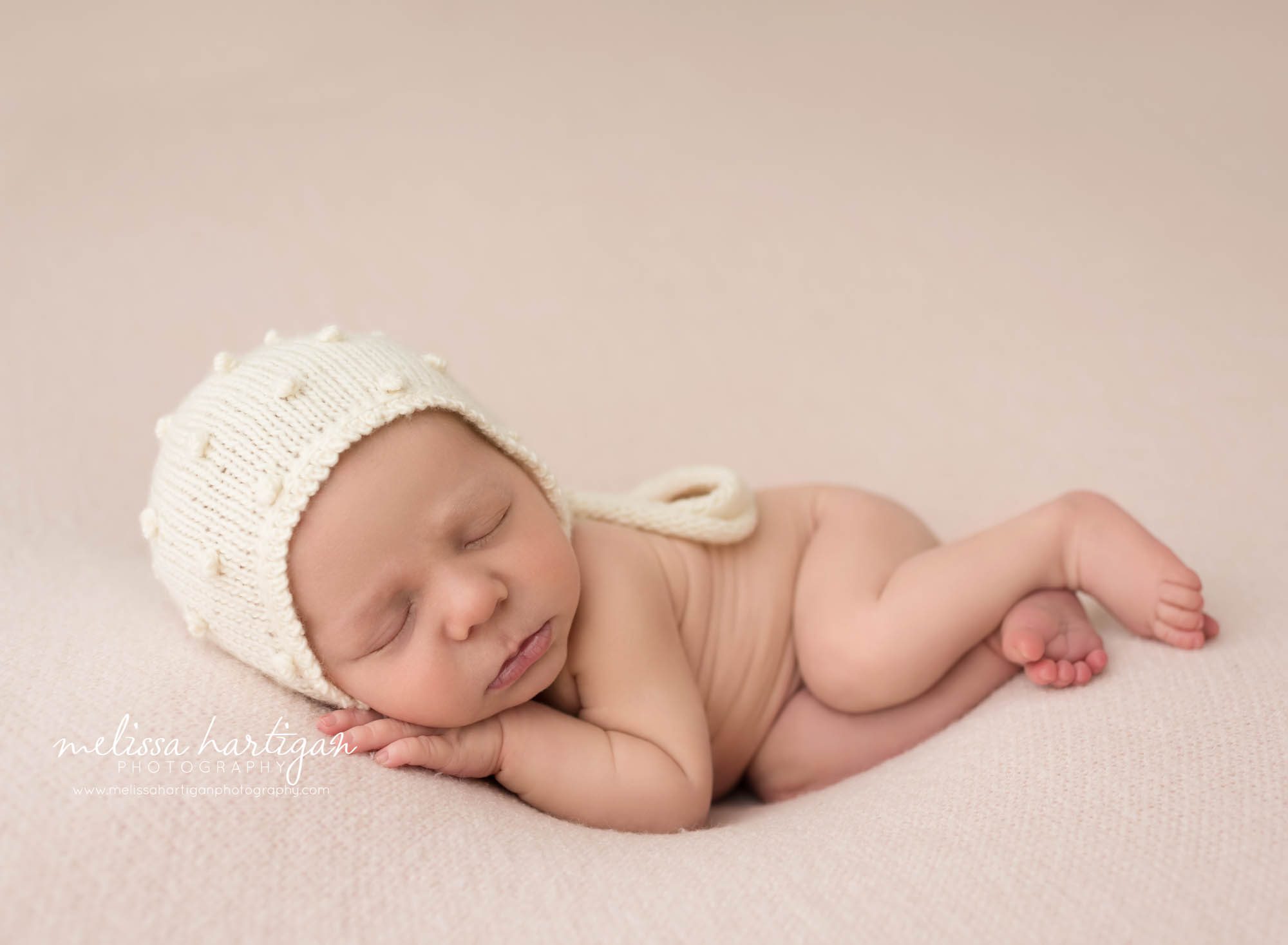 newborn baby girl posed on side wearing cream knitted bonnet newborn photography CT