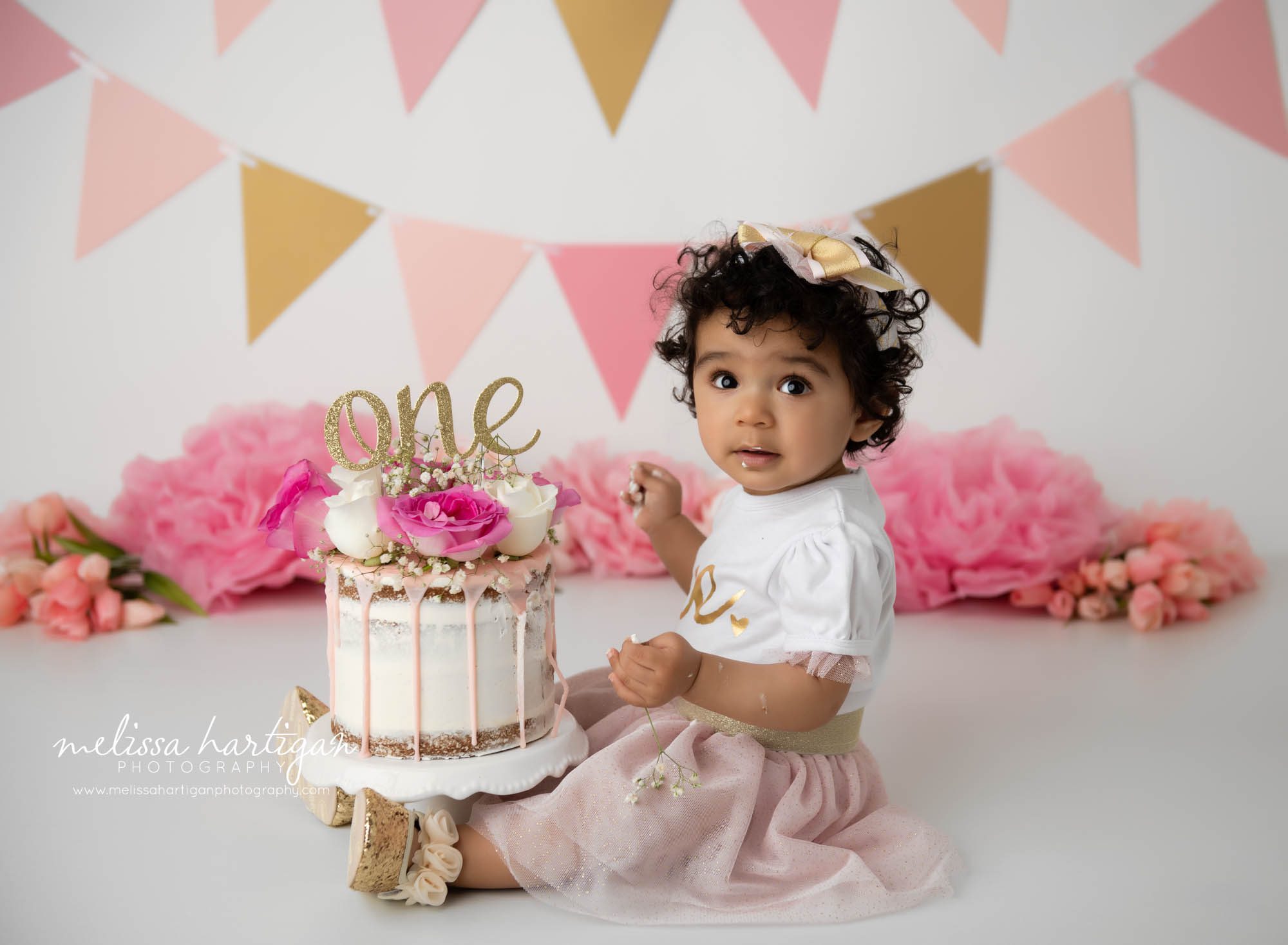 one year old baby girl sitting beside cake smash cake colchester CT baby photography