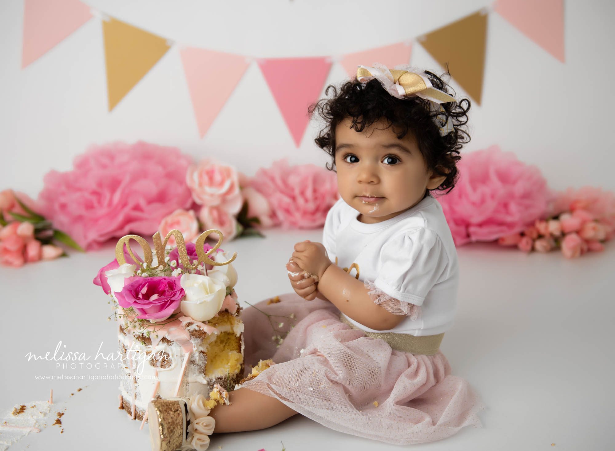 baby girl digging into and eating cake smash cake with pink flowers 