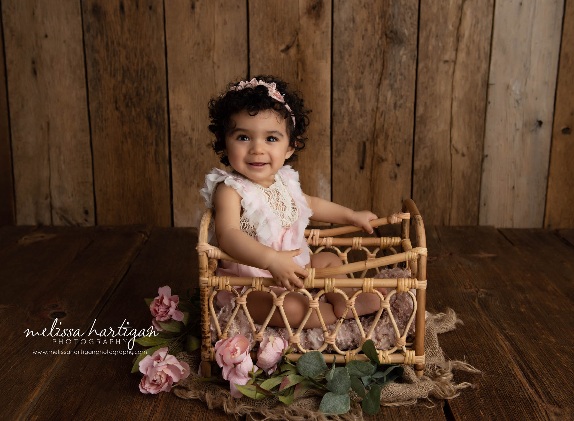 baby girl sitting in basket with pink flowers beside it happy smiling colchester CT baby milestone photographer