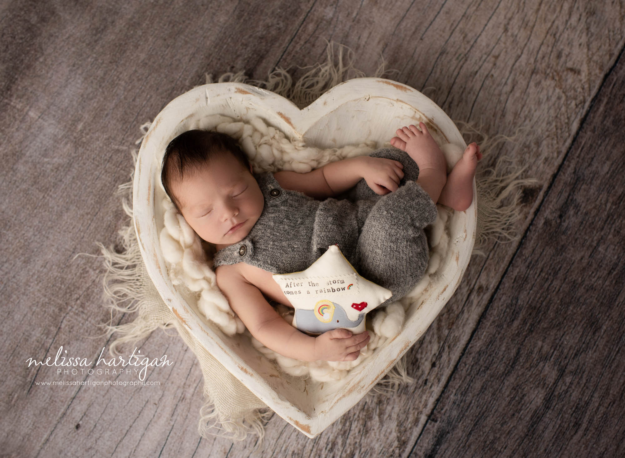 newborn baby boy posed in wooden cream heart shaped prop wearing gray outfit holding star newborn photography newington CT