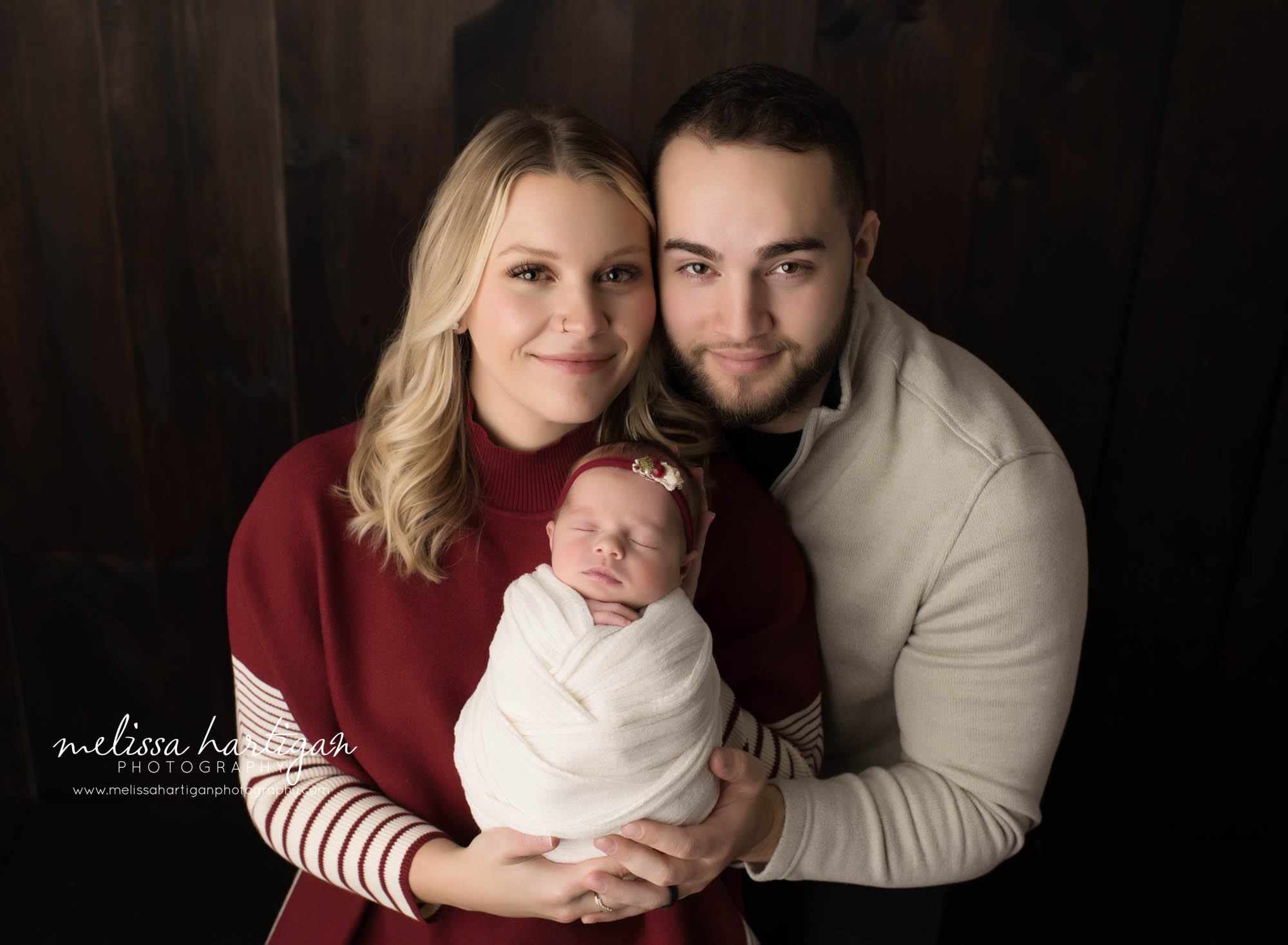 mom and dad holding baby daughter wrapped parents family pose