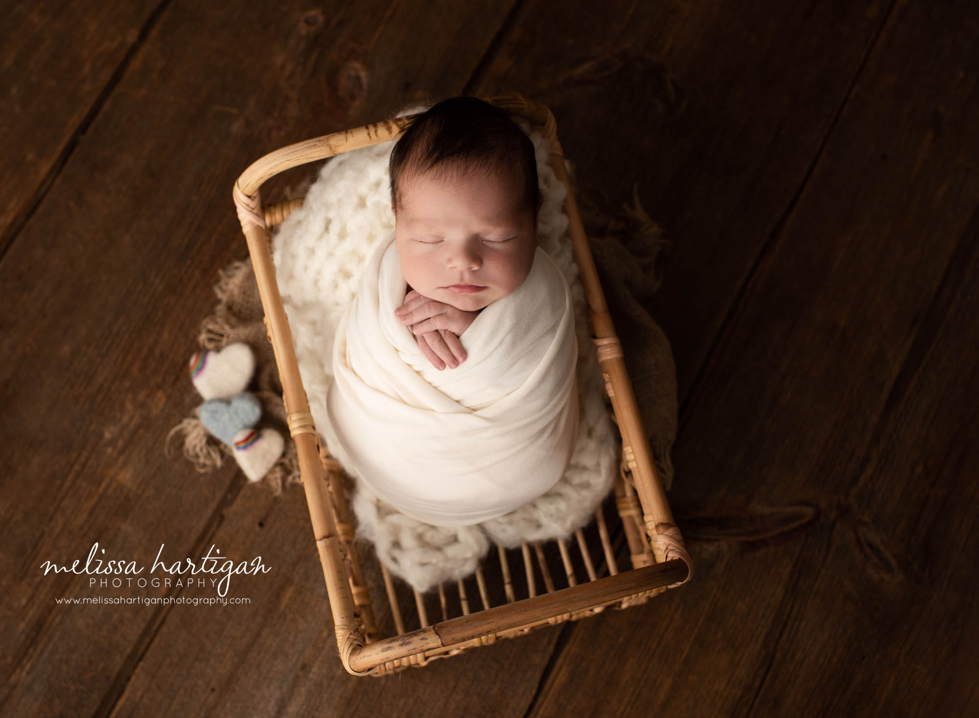 newborn baby boy wrapped in white wrap posed in basket prop