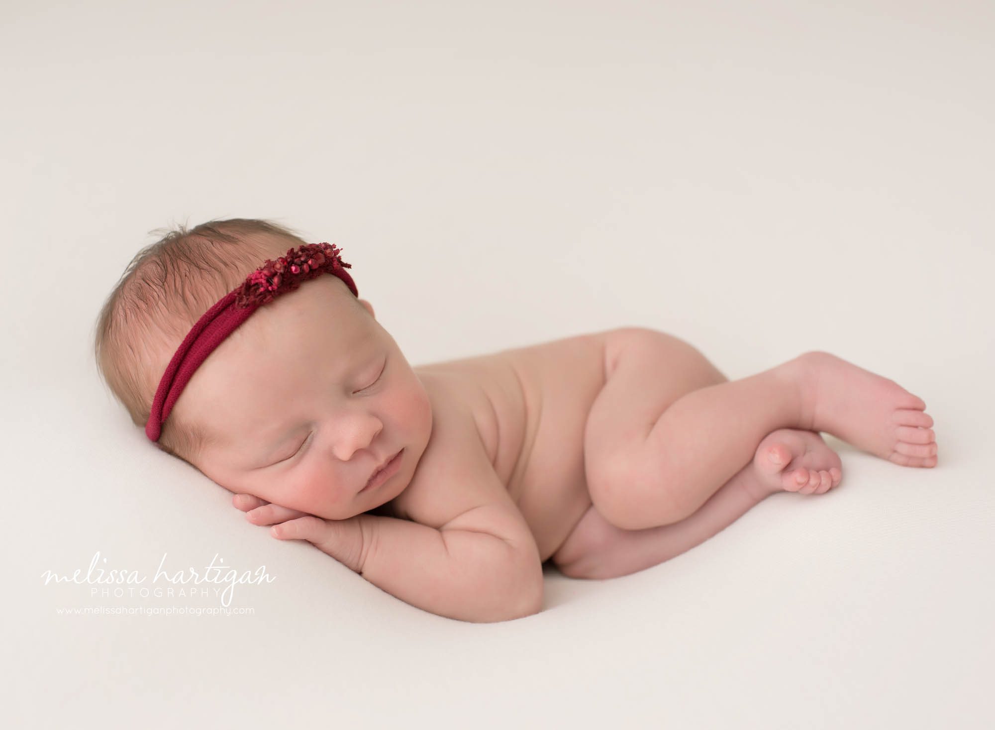 newborn baby girl posed on side wearing red headband with hand under cheek sleeping newborn photographer tolland county CT