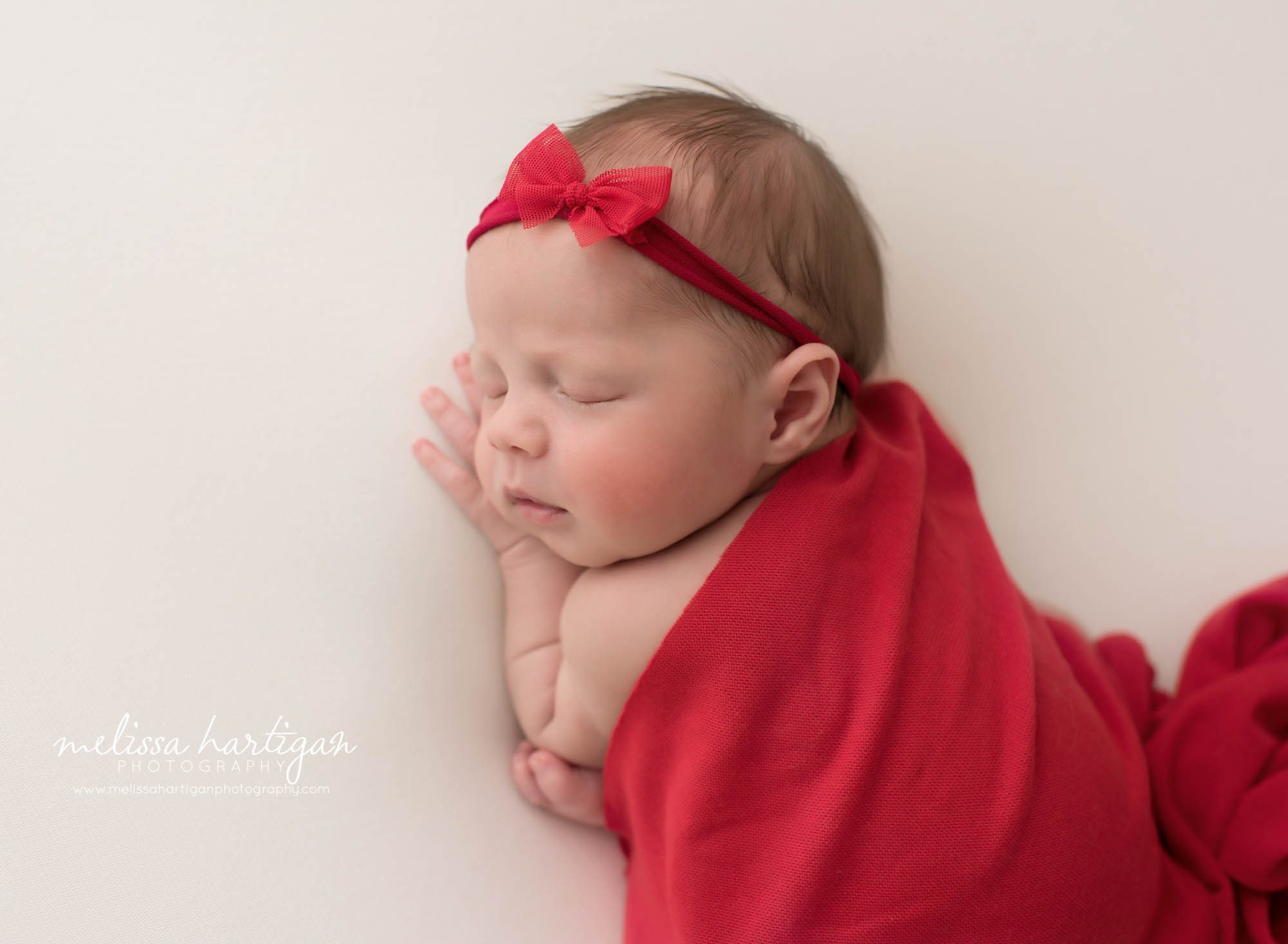 newborn baby girl posed on white backdrop with red drape layer newborn photography tolland county