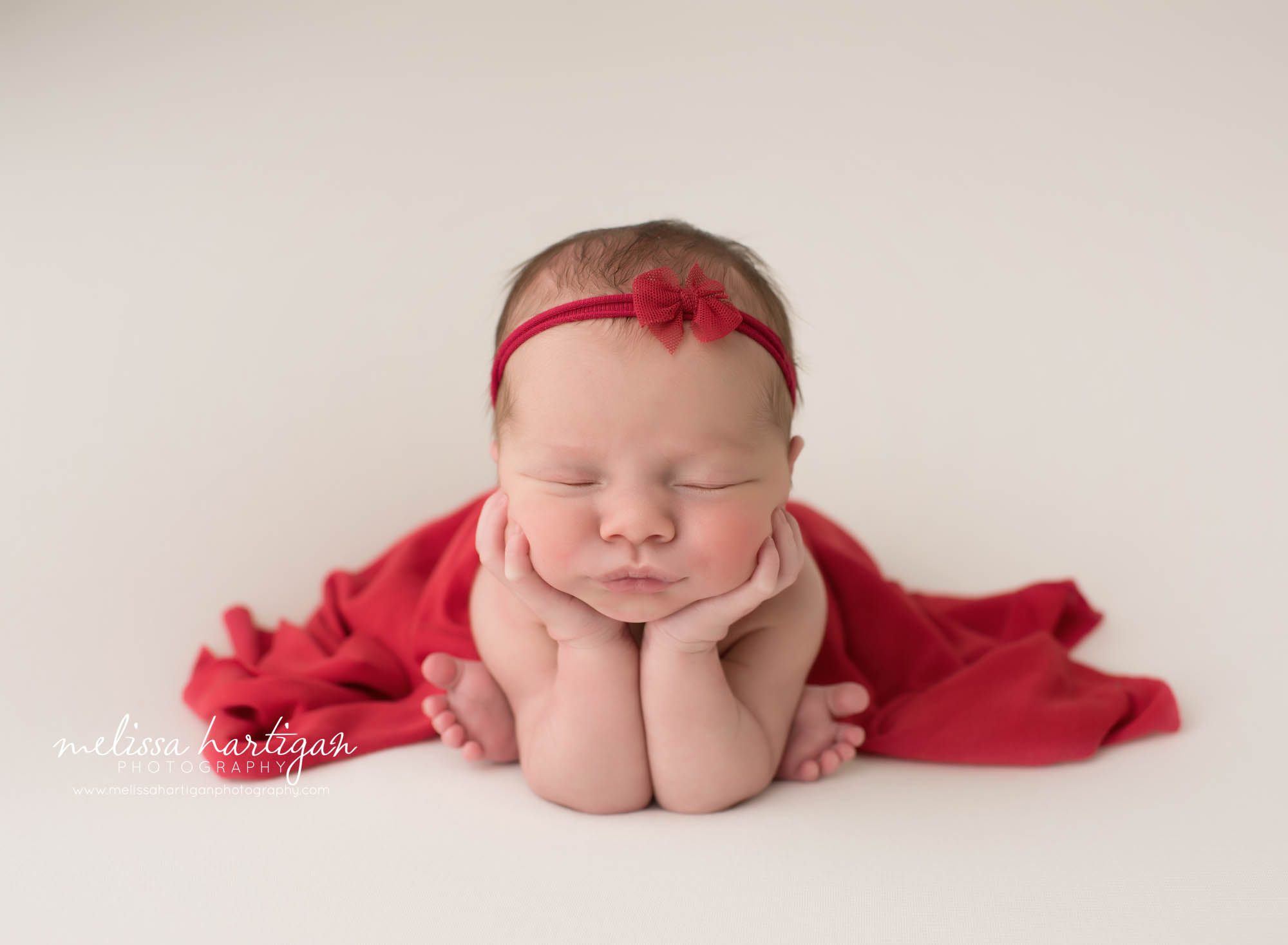 newborn baby girl posed froggy pose with red headband and red drape layer newborn photography tolland county