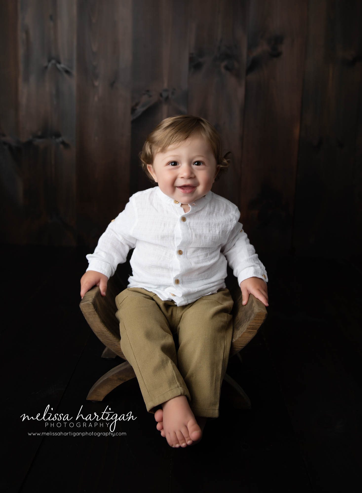 baby boy sitting on curved wooden bench in studio baby milestone session saratoga NY baby photography