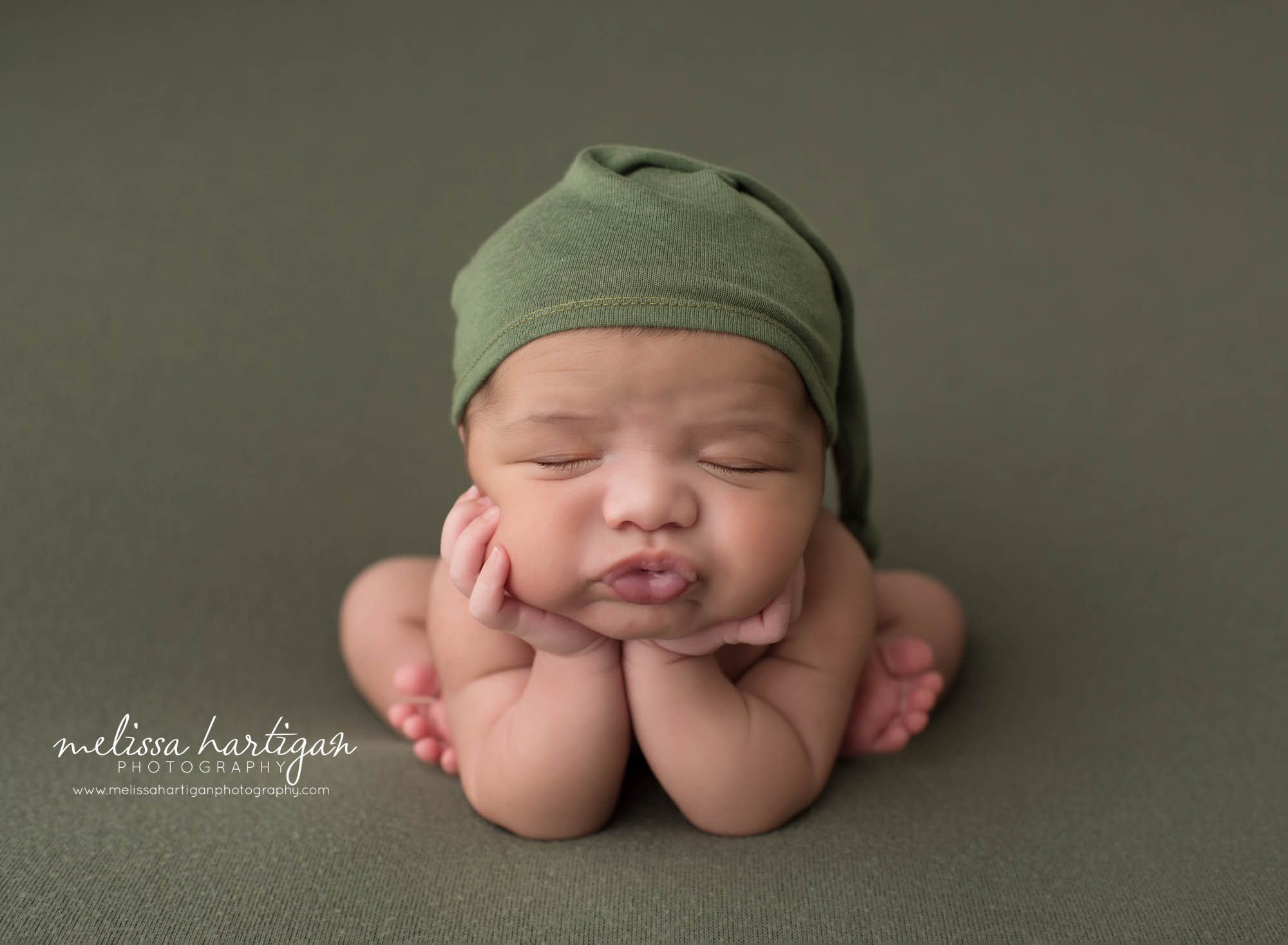 newborn baby boy posed in froggy pose wearing green sleepy cap bristol ct newborn photography