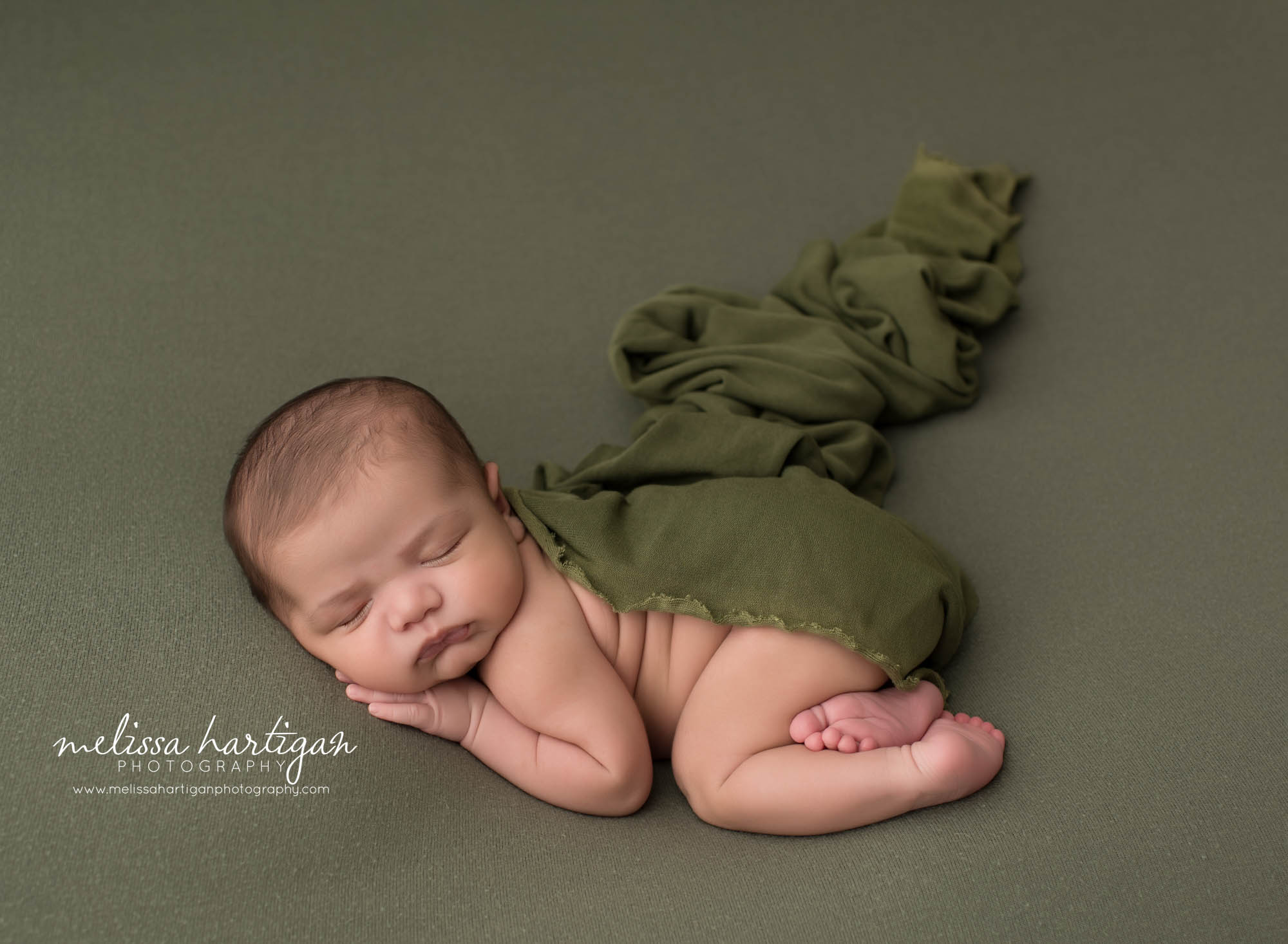 newborn baby boy posed on green backdrop with draping wrap over him ct newborn photography