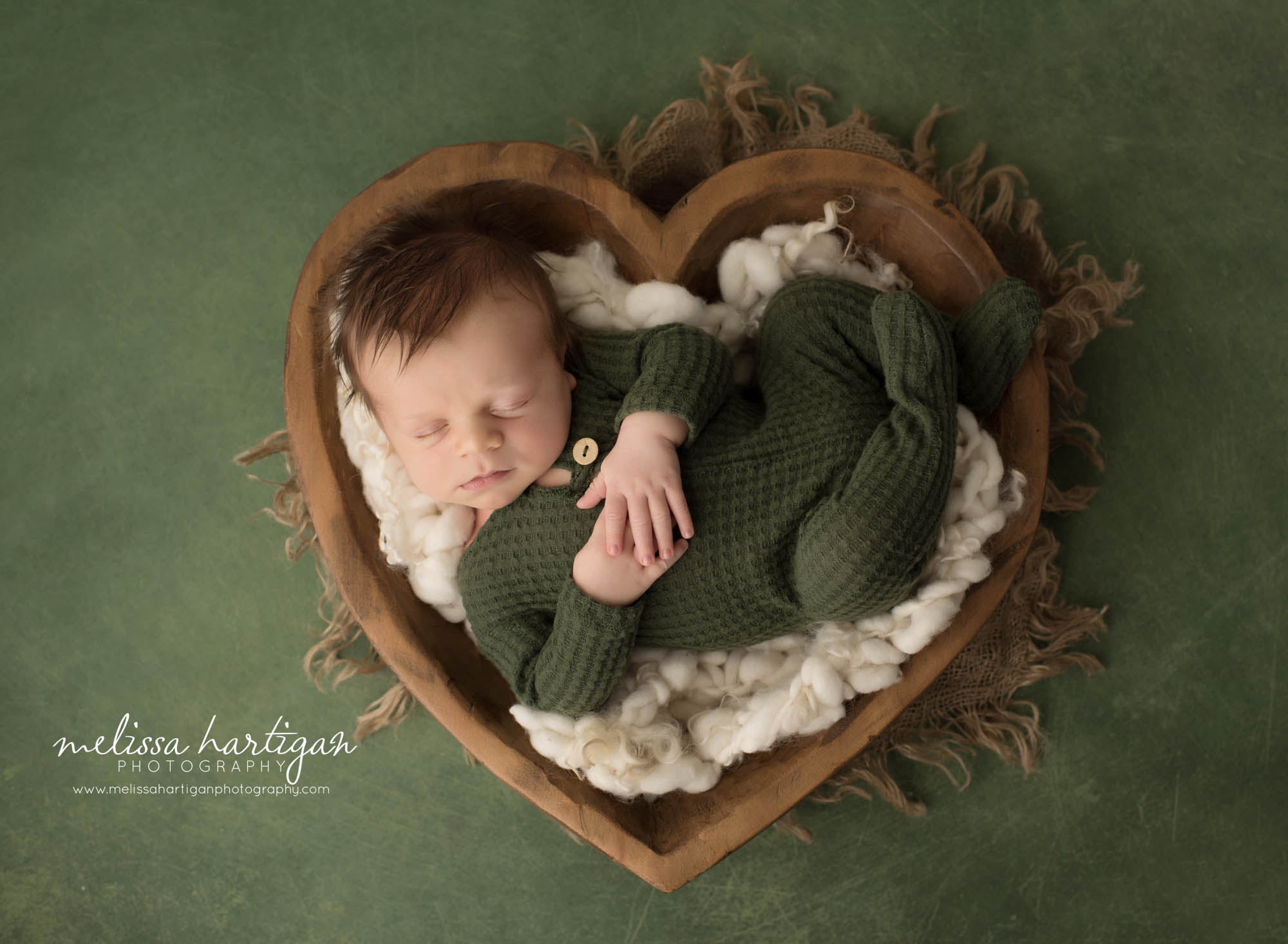 newborn baby boy wearing green newborn romper posed in wooden heart bowl prop connecticut newborn baby photography