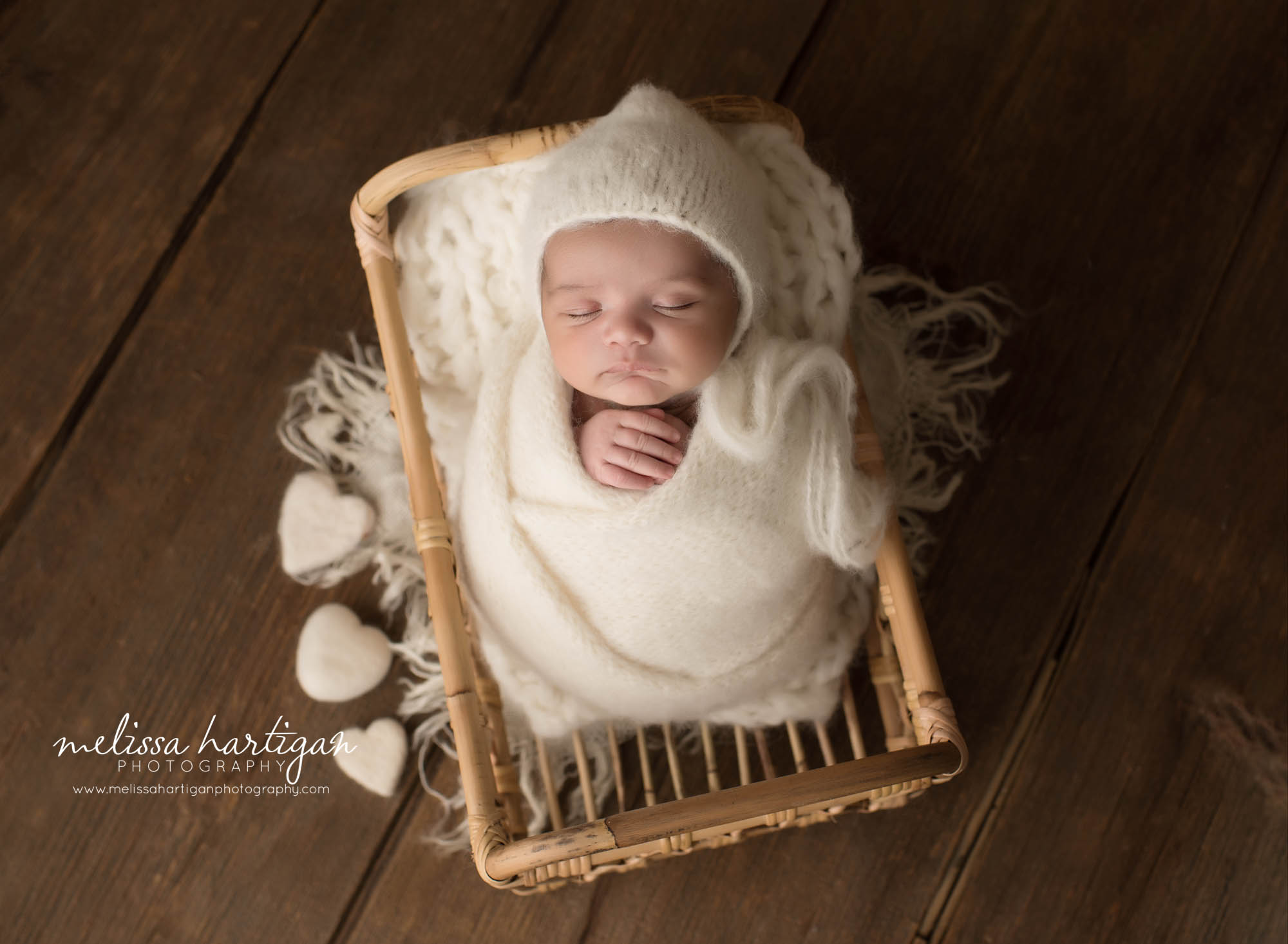 newborn baby boy wrapped in cream posed in basket with felted hearts bristol newborn photography ct