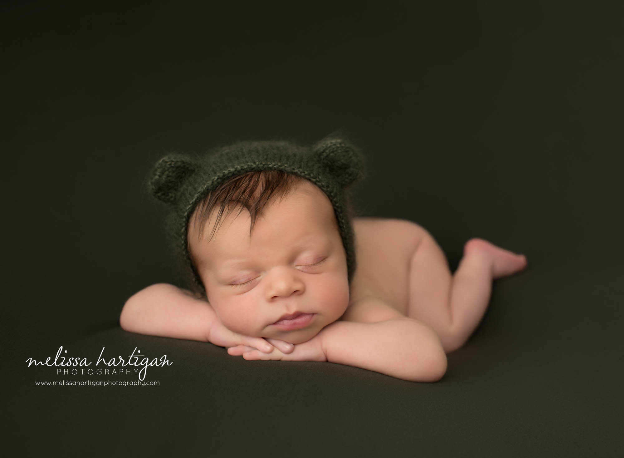 newborn baby boy posed on tummy with hands under chin wearing green knitted bear bonnet newington ct newborn photography