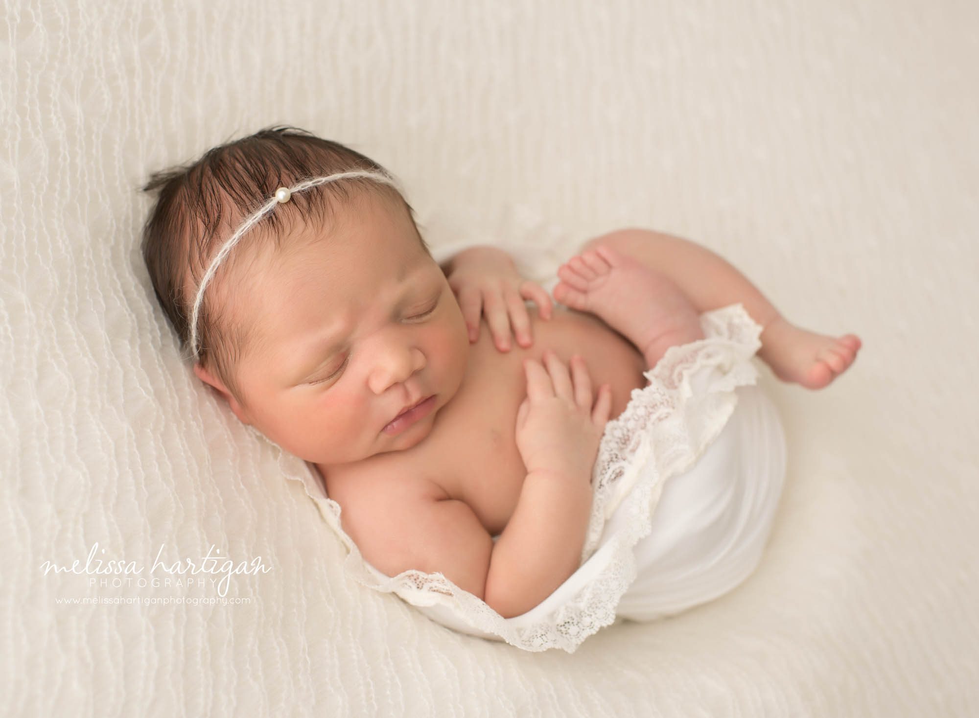 newborn baby girl laying on back with white lacey draping wrap